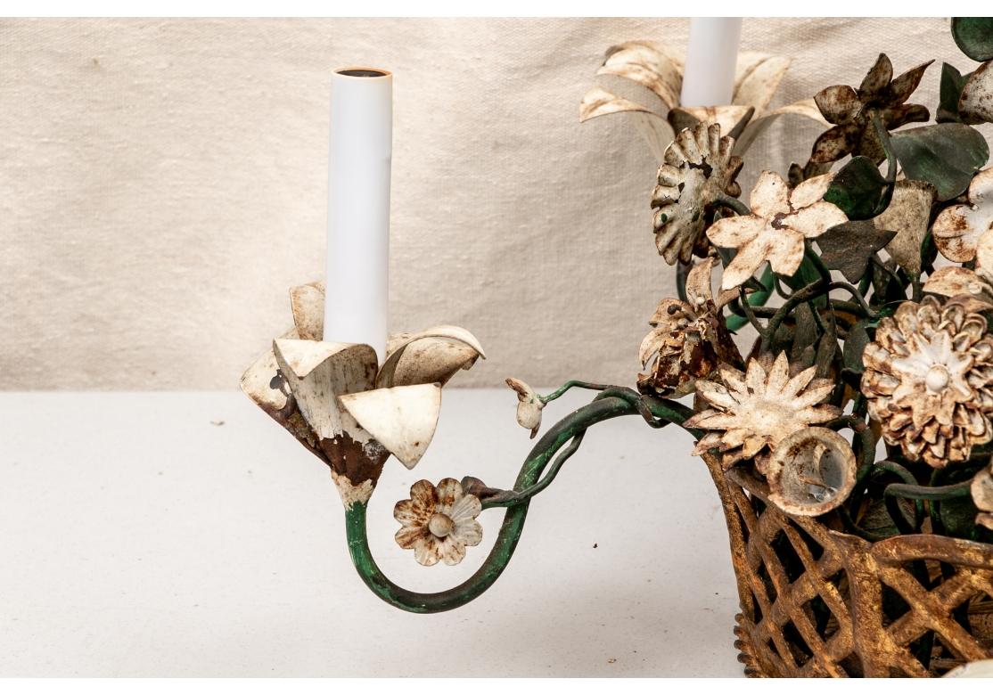 Da Michael Greer, iconico designer di New York. Un lampadario a cinque luci con finitura anticata, con lati traforati e base a trama di cesto. I cinque bracci di metallo a spirale sono verniciati in verde con luci bianche a forma di giglio. 
Due