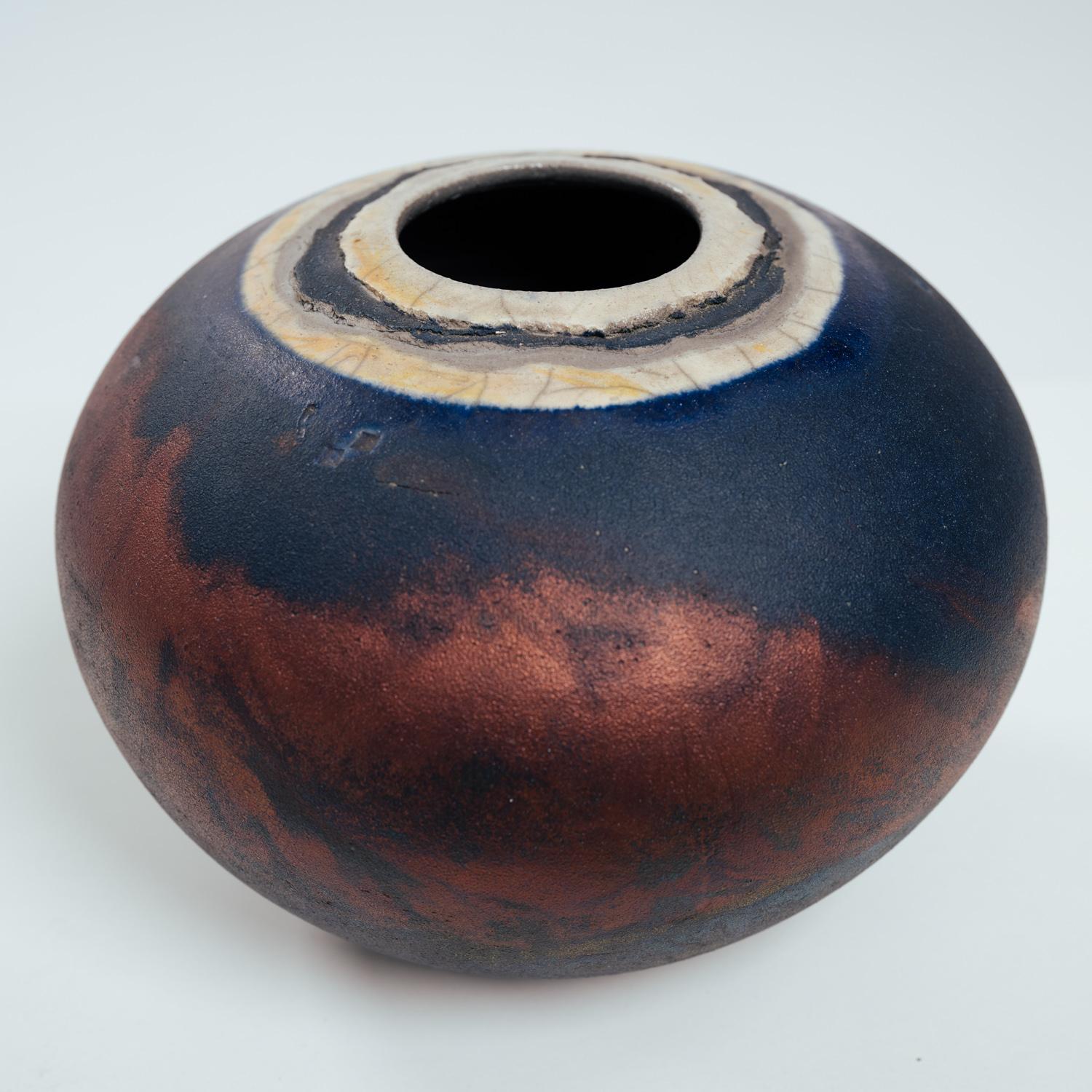 Beautiful fired handmade Raku vase by Michael Gwinup, signed with name and date.

Diameter 21 cm, height 14 cm.
Unique piece with pearl coloured copper blue black green firing.