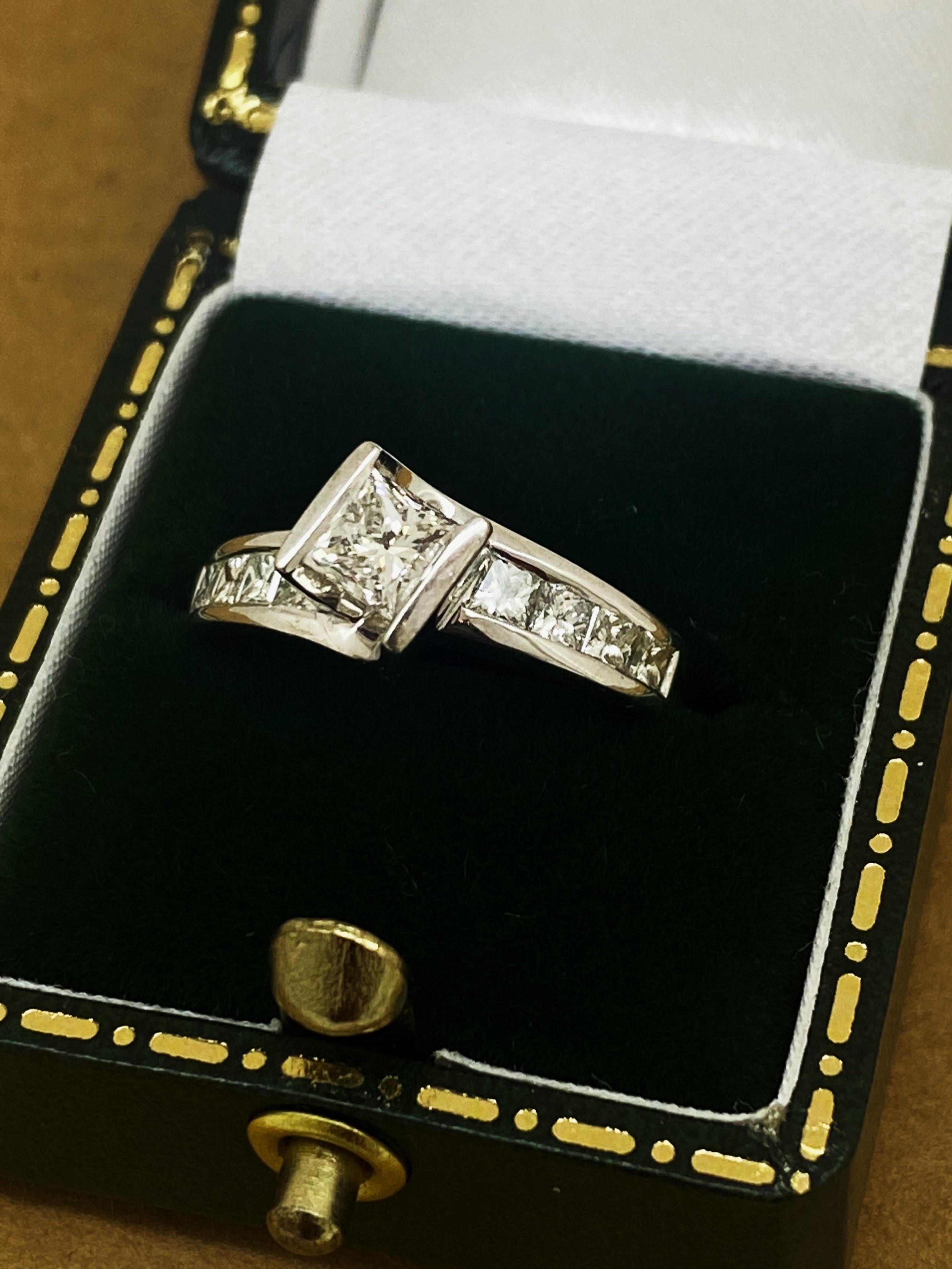 De diseño atemporal y visualmente impactante Solitario con acentos 
esta pieza es de canal central/barra con 
un brillante diamante talla princesa - 
de impresionante tamaño - 0,70 ct aprox,
mide 5 mm 
de color G, claridad VS y brillo como el sol,