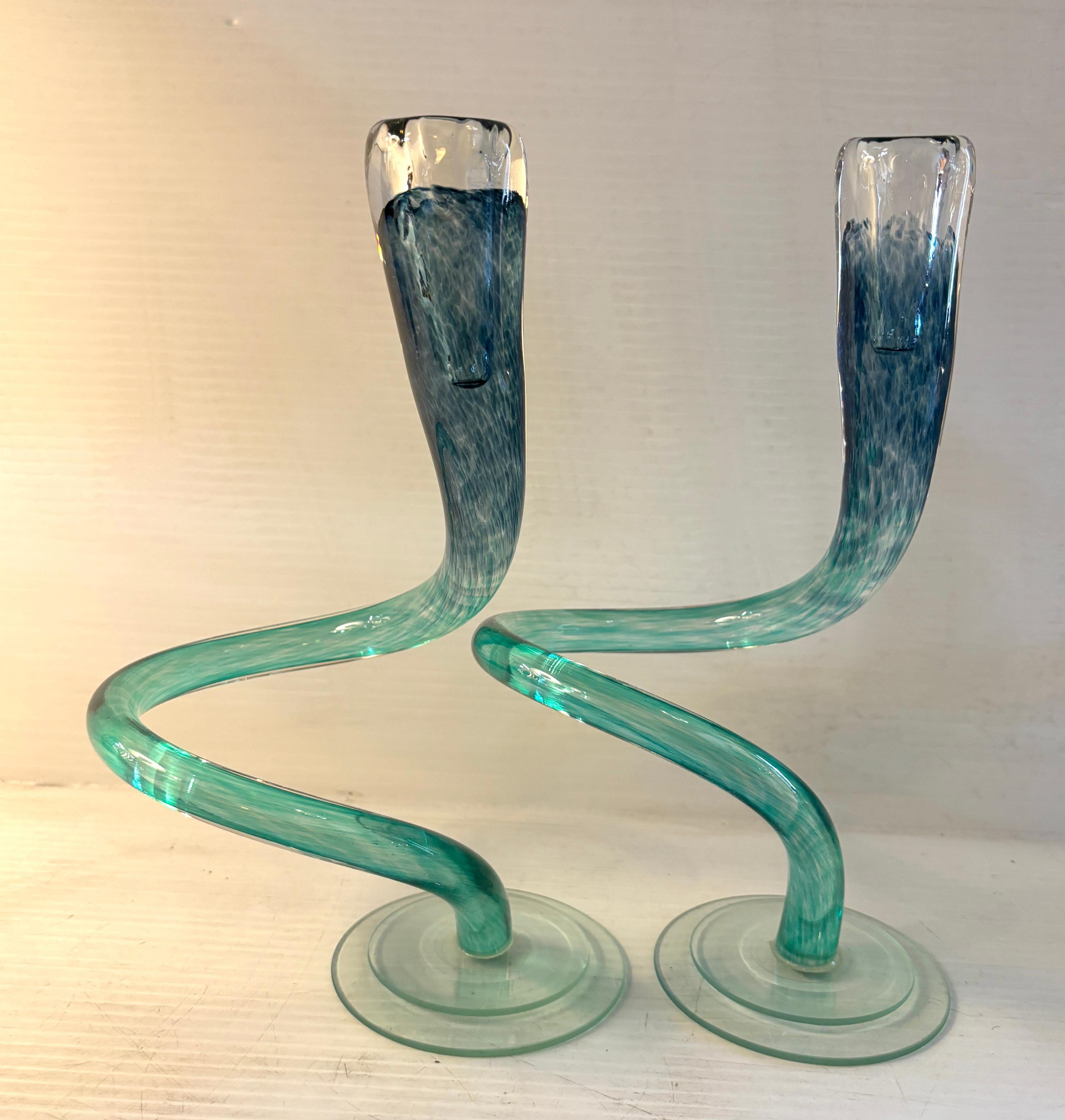 Pair of twisting candlesticks by artist Michael Hudson. Made from hand blown glass, with one of a kind coloring. 
Please confirm location NY or NJ