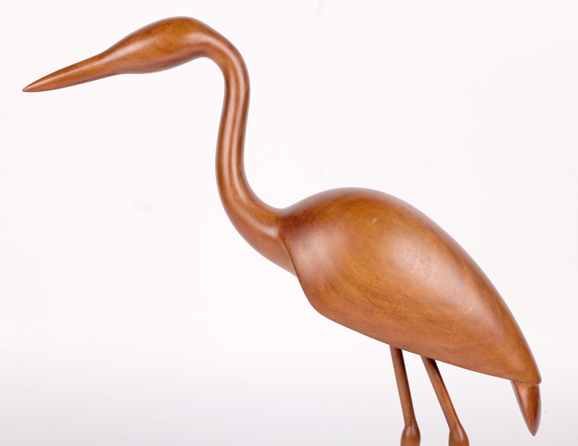 A stunning modern hand carved figure of a heron by renowned British wood carver Michael John Crook and dating from the latter 20th or very early 21st Century. The figure stands mounted on a hard wood oval shaped base representing water with the feet