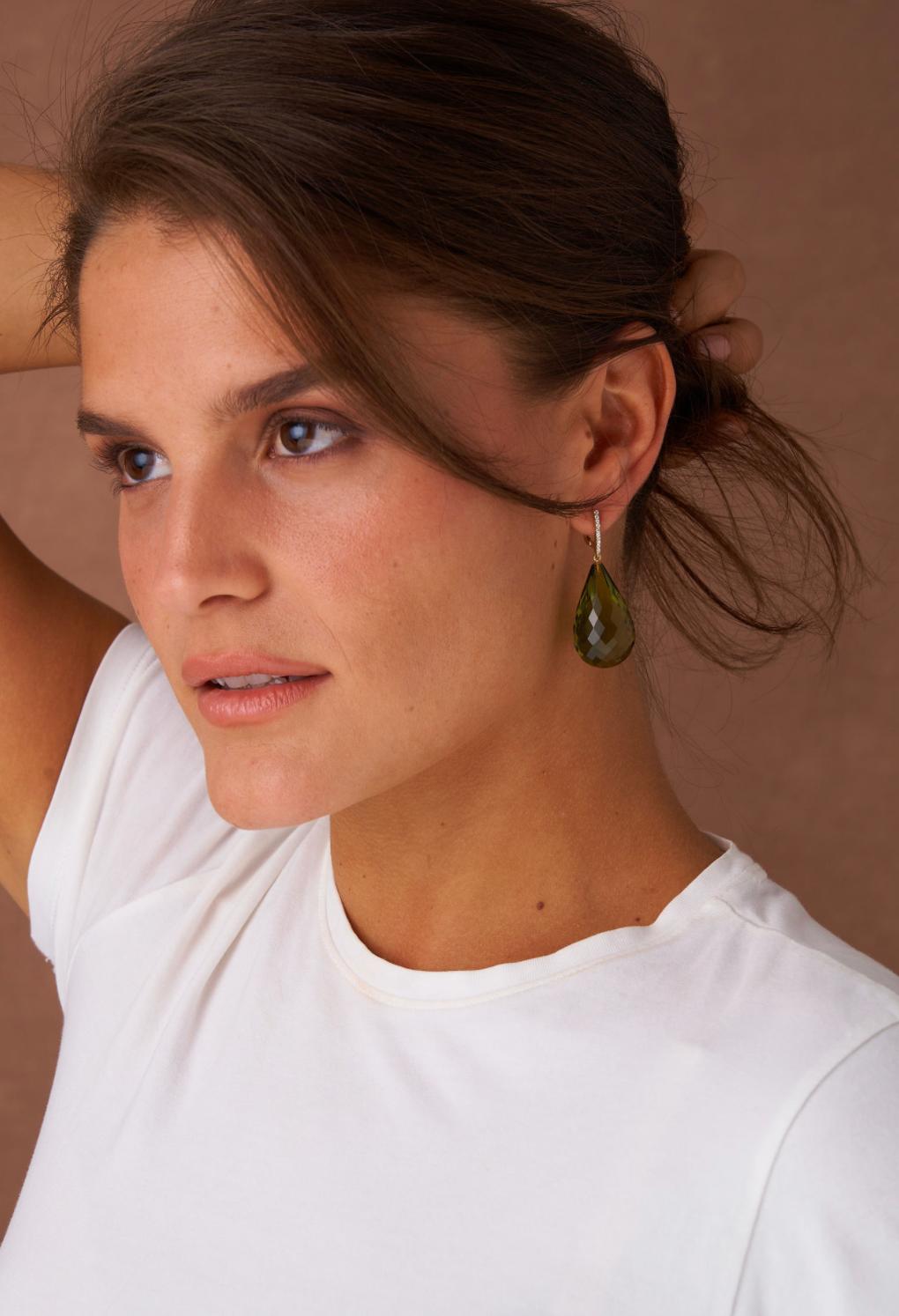 These earrings feature stunning briolette-cut green amber drops that dangle elegantly from a delicate diamond set top. The warm tone of the amber is beautifully offset by the sparkling diamonds, adding a touch of glamour to the organic design.  The