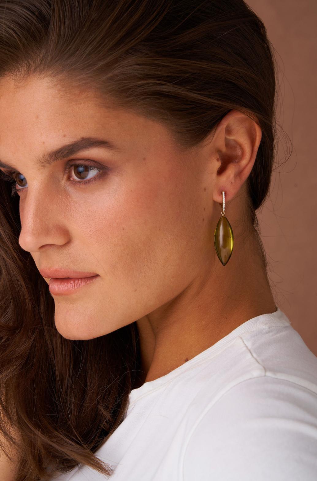 Introducing stunning green amber and diamond drop earrings, by Michael Kanners. Crafted in 14k gold, the organic design showcases vibrant amber stones suspended from dazzling diamonds. The delicate drop style catches the light beautifully, making