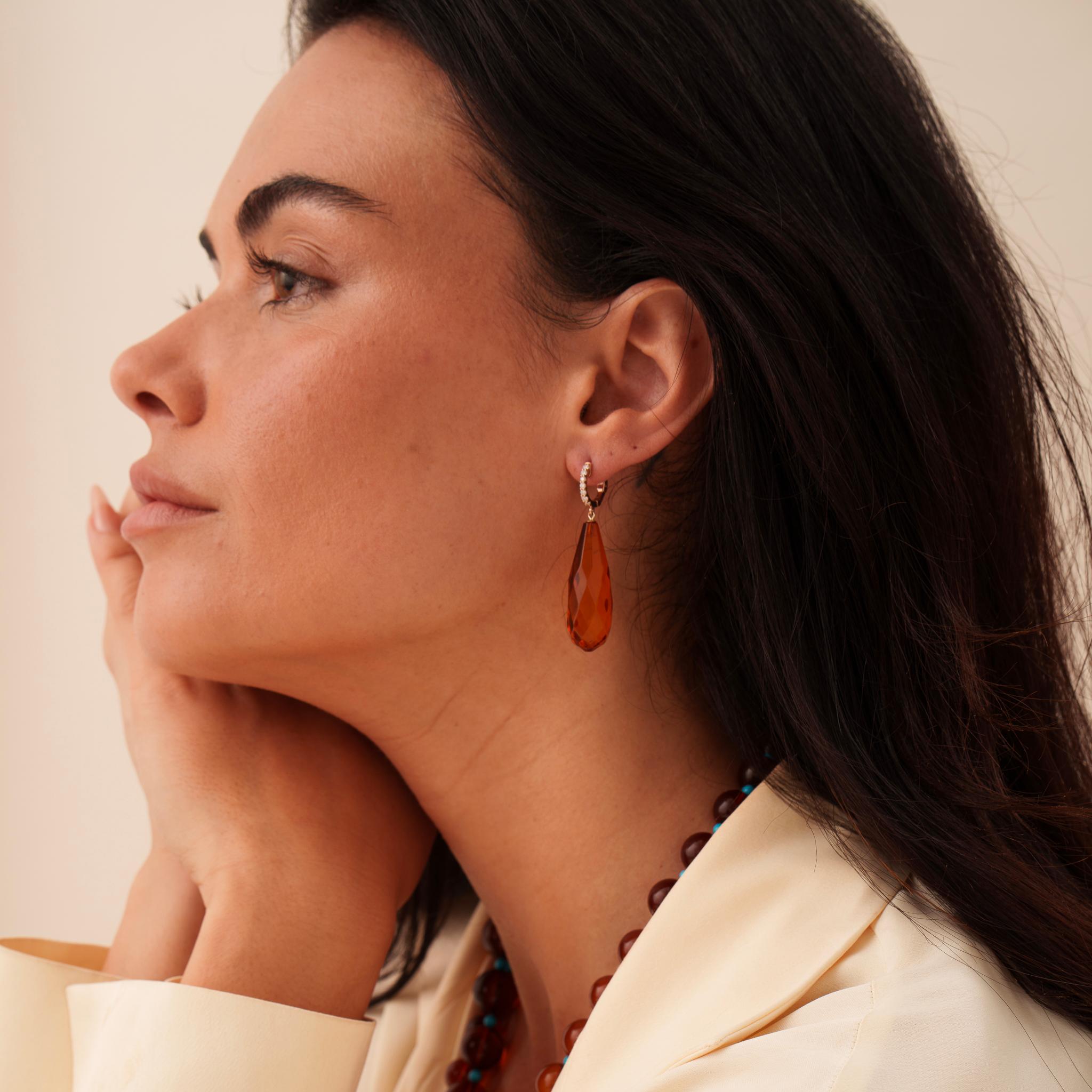Striking cognac color amber drop earrings, adorned with exquisite diamonds and crafted in a warm rose gold.  The faceting of the amber is simply mesmerizing, catching the eye from every angle.  The earrings are expertly designed to hang gracefully