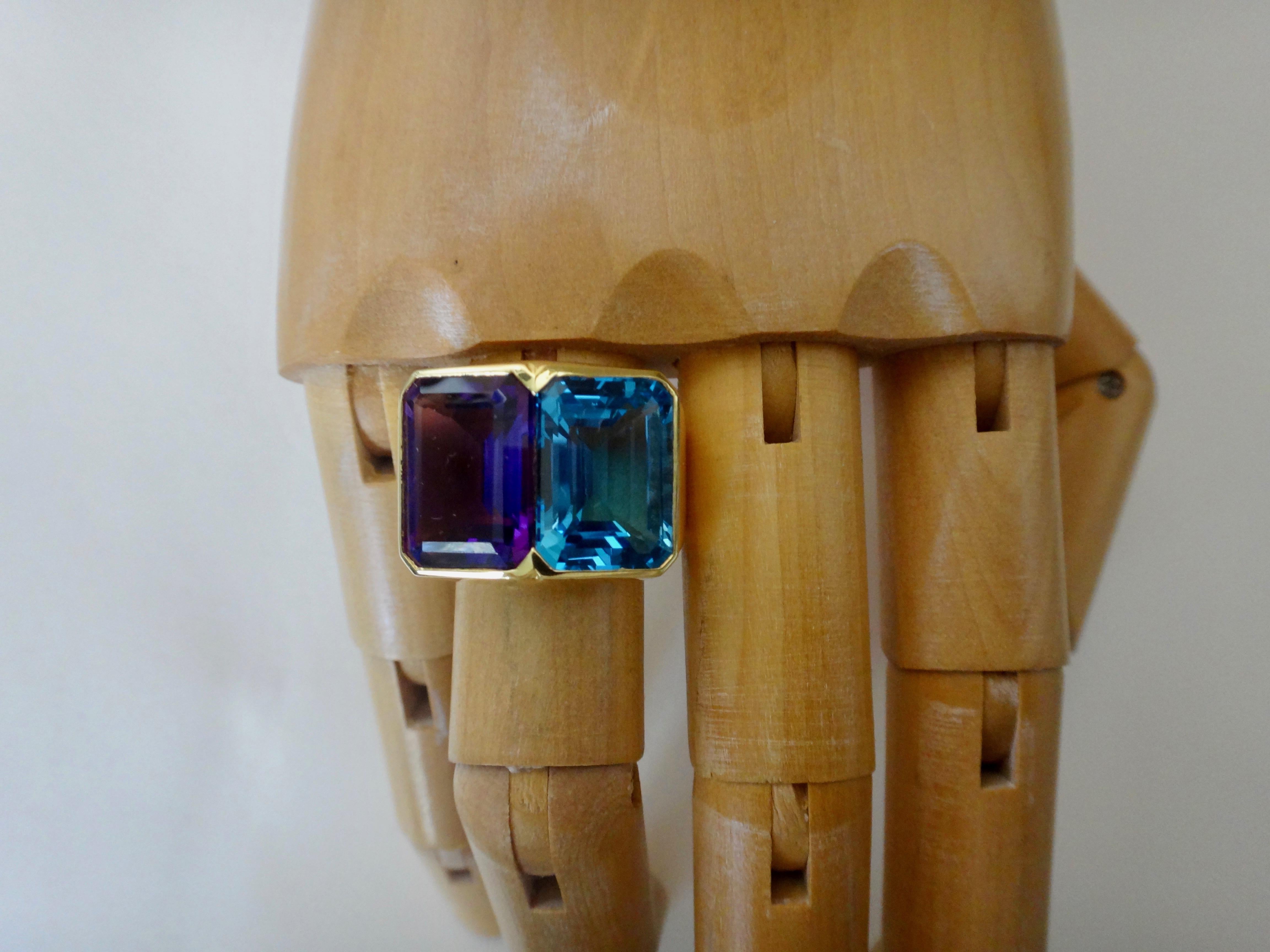 Perfectly matched and highly complimentary in color, these emerald cut London blue topaz and deep purple amethyst (origin both: Brazil) are set in a carefully crafted 18k yellow gold cocktail ring.  The durability of these two gems would make this