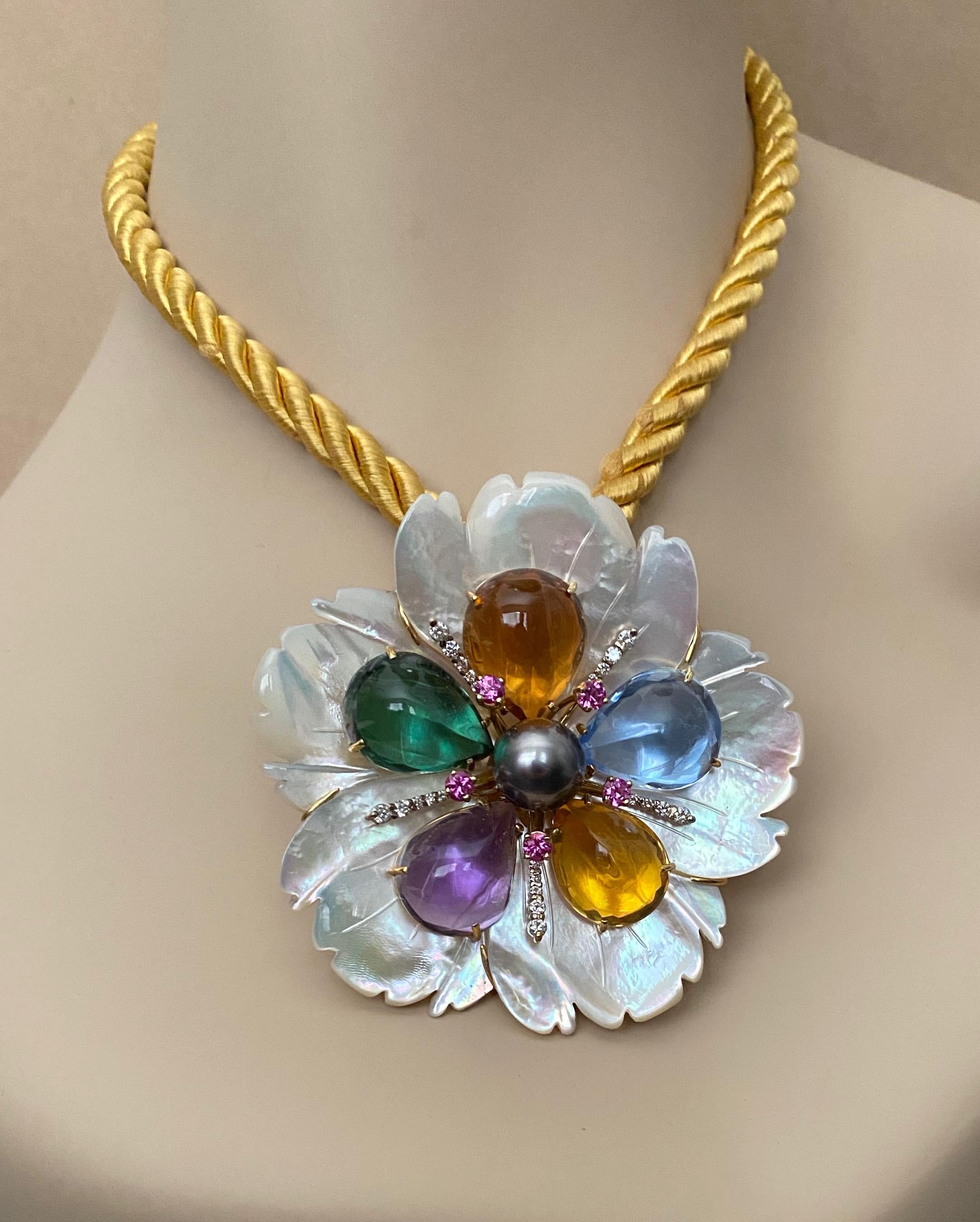 A carved mother-of-pearl flower forms the foundation for this elegant one-of-a-kind combination pendant and brooch.  Pear shaped cabochons of amethyst, citrine, blue topaz and green amethyst along with pink sapphires, diamonds and a generously sized
