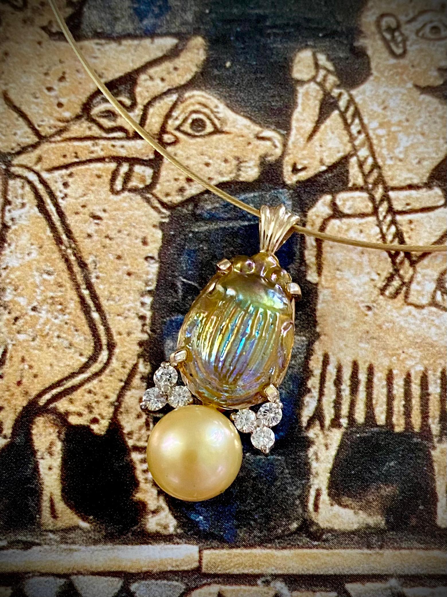 An antique Louis Comfort Tiffany opalized glass scarab is featured in this distinguished drop pendant.  The beautifully detailed scarab possesses a fantastic opal-like play of light reflecting colors of blue, green and lavender all on the golden