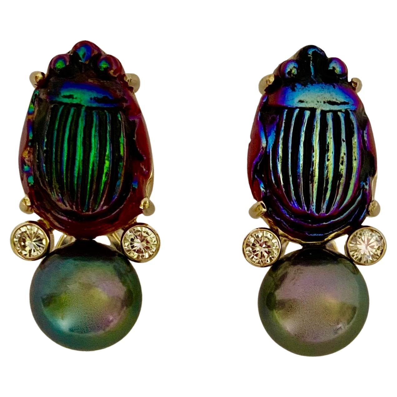 A pair of antique Louis Comfort Tiffany Favrile glass scarabs are featured in these dramatic drop earrings.  The beautifully detailed scarabs possess a lustrous rainbow-like play of colors typically found in Tiffany glass.  Those colors are picked
