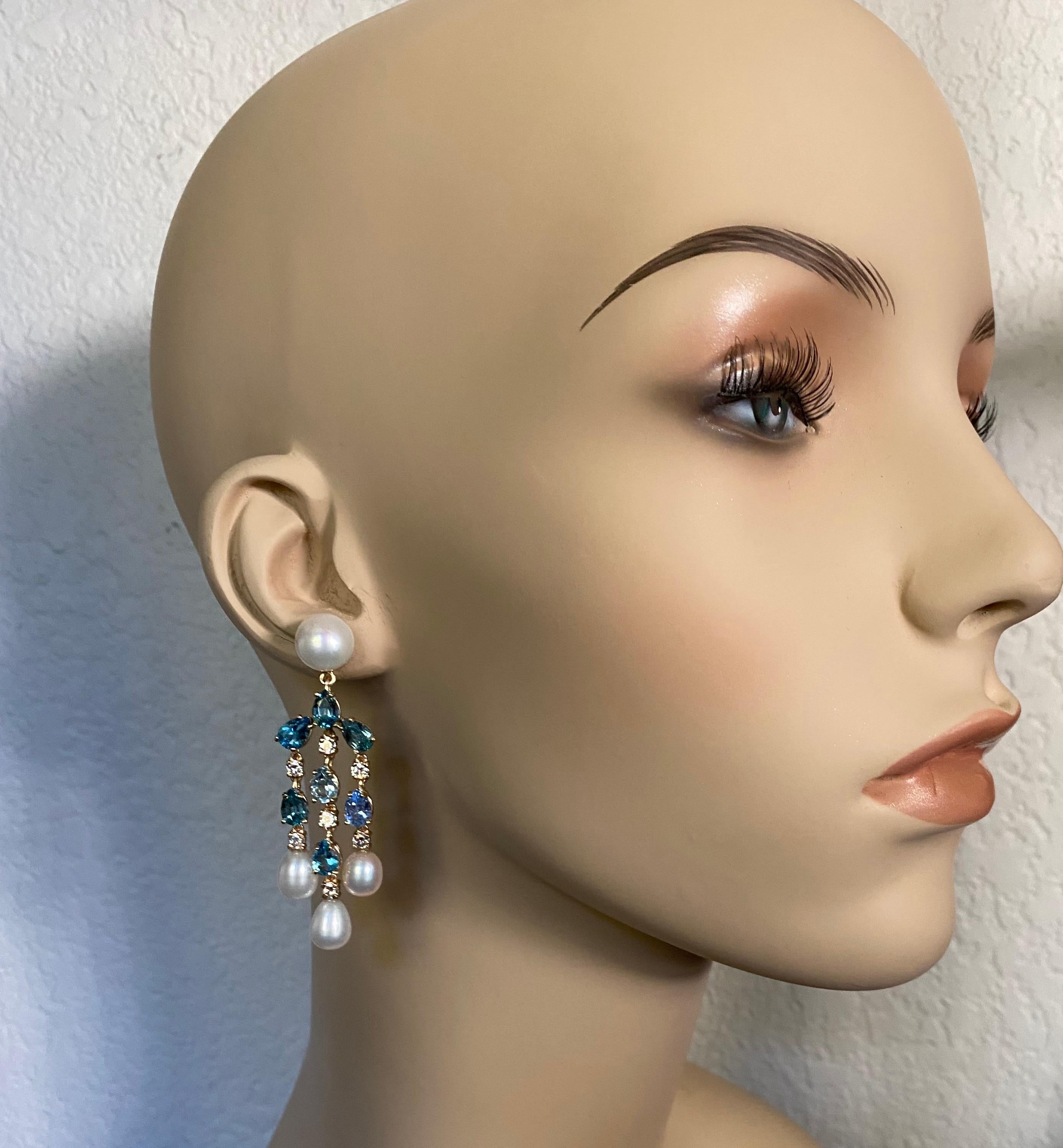 A medley of blue gems are combined with diamonds and pearls is these distinctive chandelier earrings.  Pear shaped aquamarine, tanzanite, zircon and blue topaz have been artfully blended to create and icy waterfall effect.  Brilliant cut diamonds