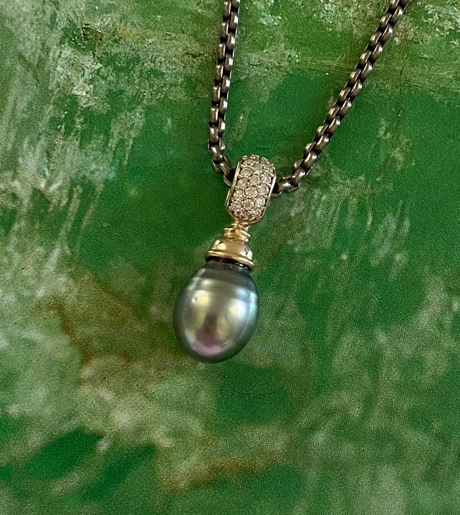 La perle de Tahiti est mise en valeur dans cet élégant pendentif en forme de goutte.  La perle est d'une belle couleur gris moyen avec des nuances de vert et de bleu.  La gemme présente quelques petites fossettes mais possède un riche lustre qui en