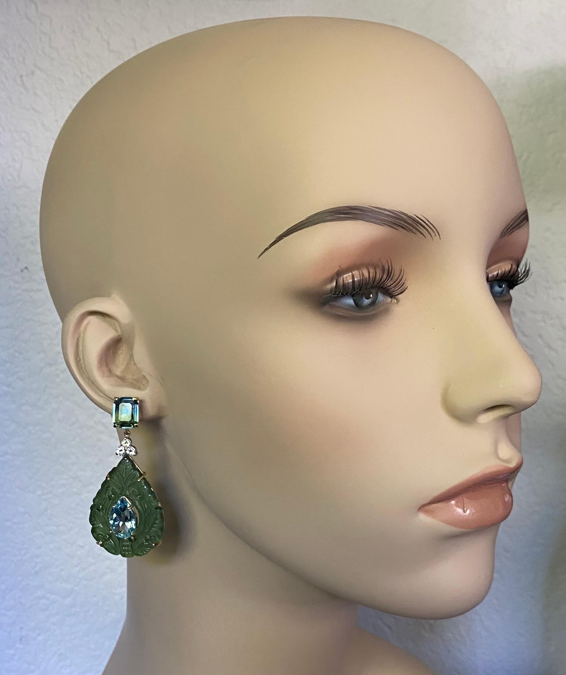 Multi-colored gems are featured in these dramatic dangle earrings.  Topping the composition are bi-colored topaz in shades of green and blue.  Pear shaped sky blue topaz are mounted within carved plaques of green jade (origin: China).  Accenting the