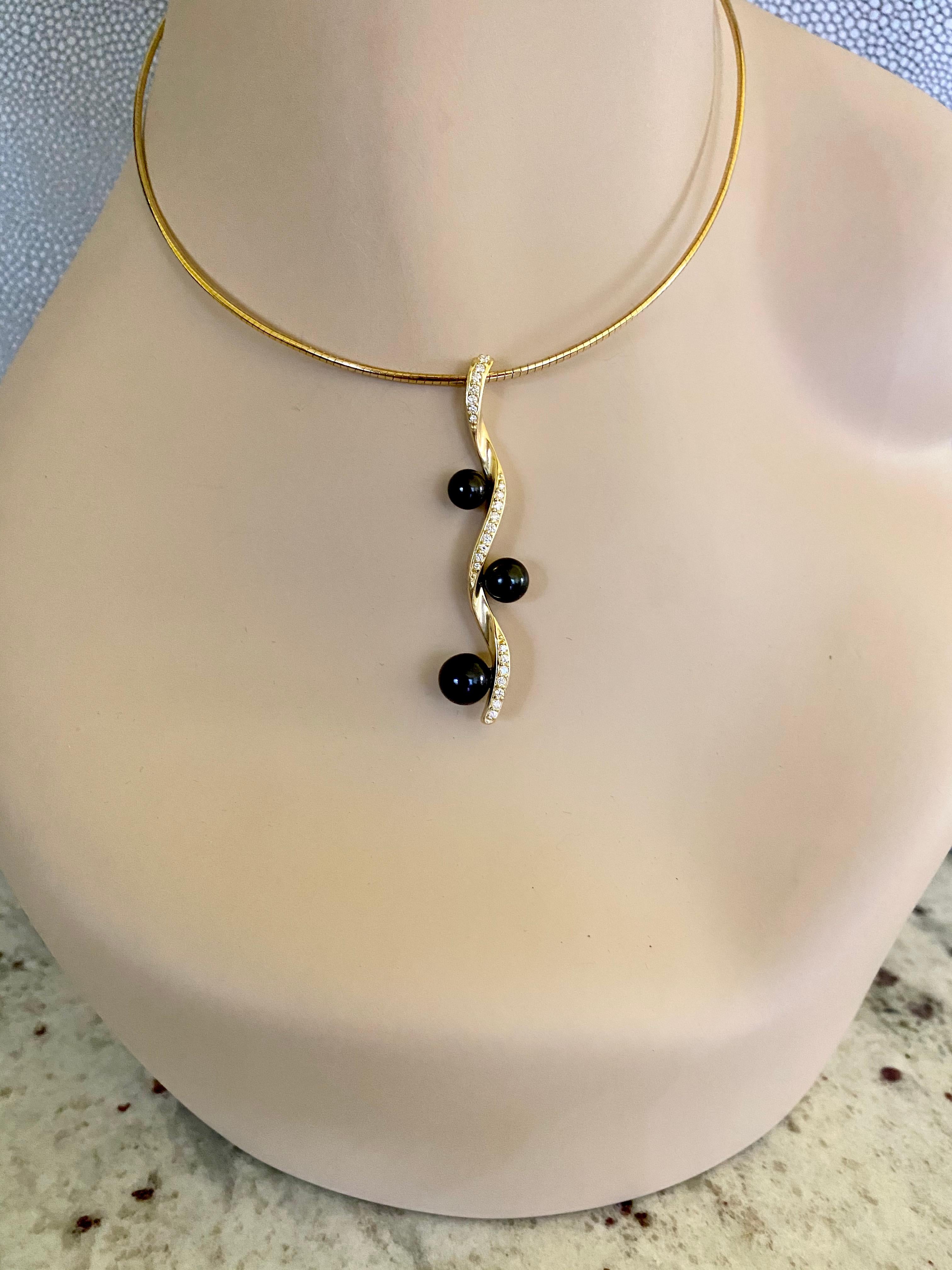 Black Akoya pearls (origin: Japan) in graduated sizes are featured in this unique Helix pendant.  The pearls are gem quality and possess a rich luster.  White diamonds are pave set within the curves of the twisted 18k yellow gold.  The pendant hangs