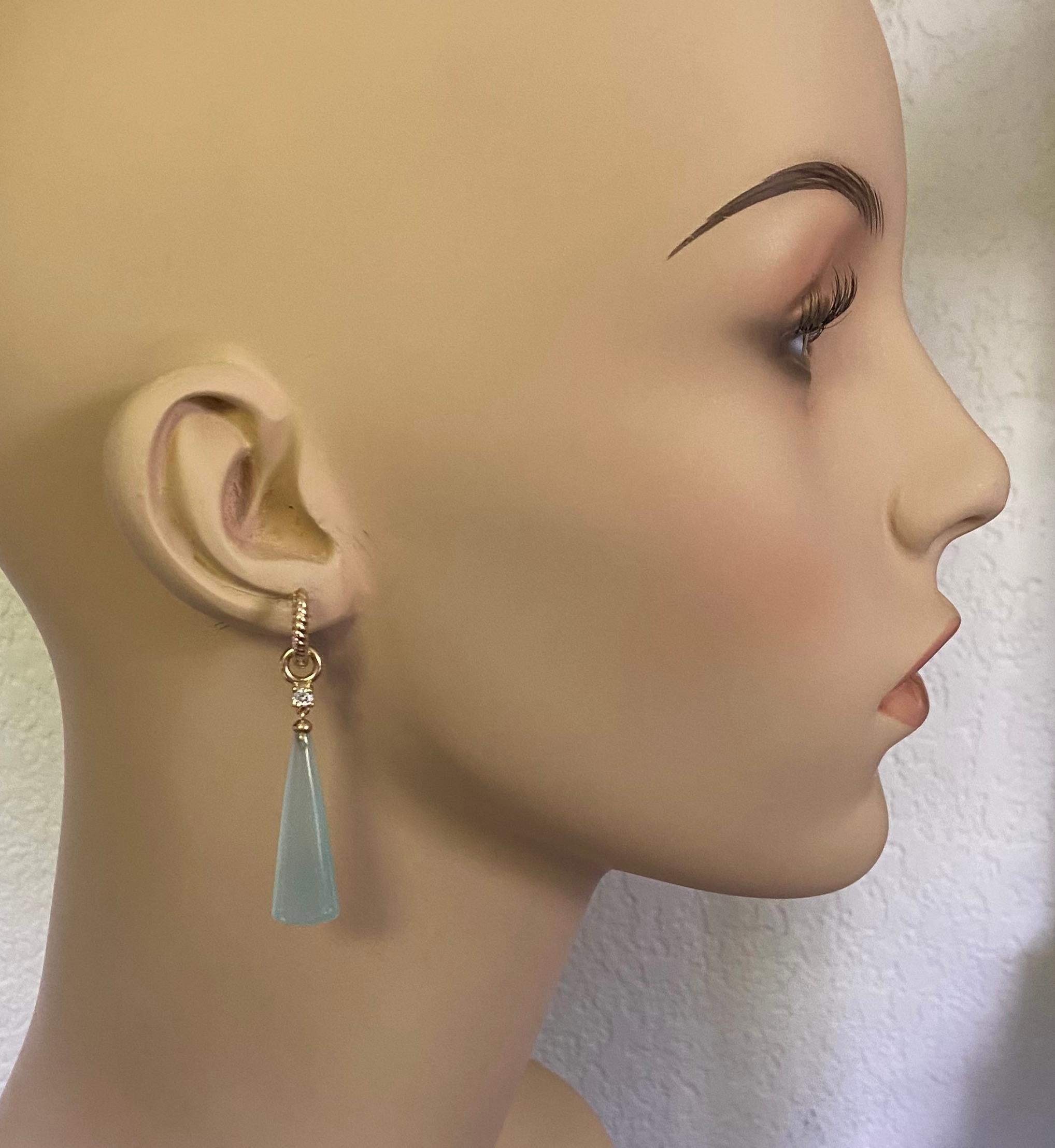 Blue chalcedony is showcased in these delicate dangle earrings.  The chalcedony (origin: Brazil) has been expertly cut and polished into smooth briolette with unusually finished blunt ends.  The mounts have been embellished with white diamonds.  The