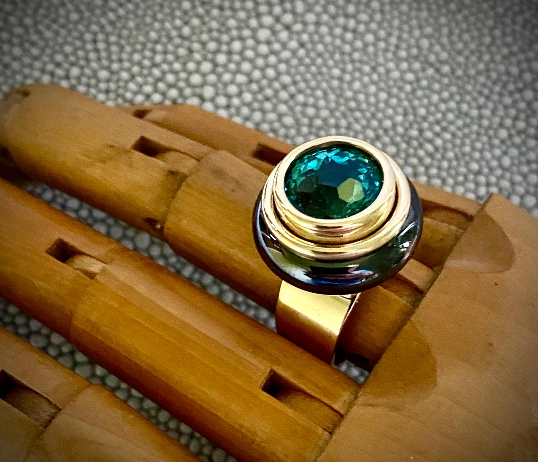 Este anillo de cóctel informal presenta un topacio azul/verde.  El topacio de talla redonda (origen: Brasil) es de un vibrante color turquesa y está facetado en una configuración de 