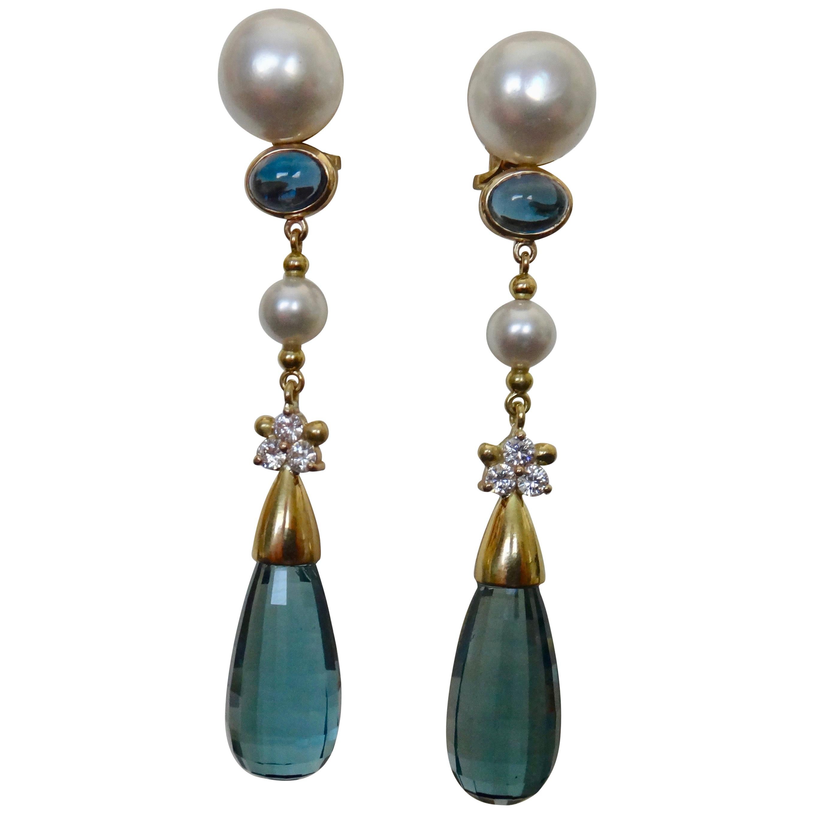 Dramatic dangle earrings are created in a cool palette consisting of large blue topaz briolettes, white button pearls, white diamonds, white Akoya pearls and cabochons of blue topaz.  The four pearls are pure white and are blemish free.  The topaz