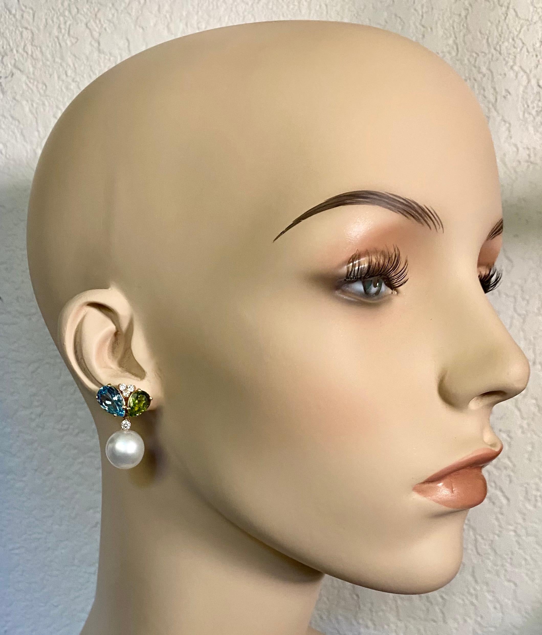 Blauer Topas und Peridot werden mit den Paspaley-Südseeperlen zu diesen eleganten Ohrhängern kombiniert.  Beide Edelsteine sind birnenförmig mit intensiver Farbsättigung und sind gut geschliffen und poliert.  Sie werden durch Büschel weißer