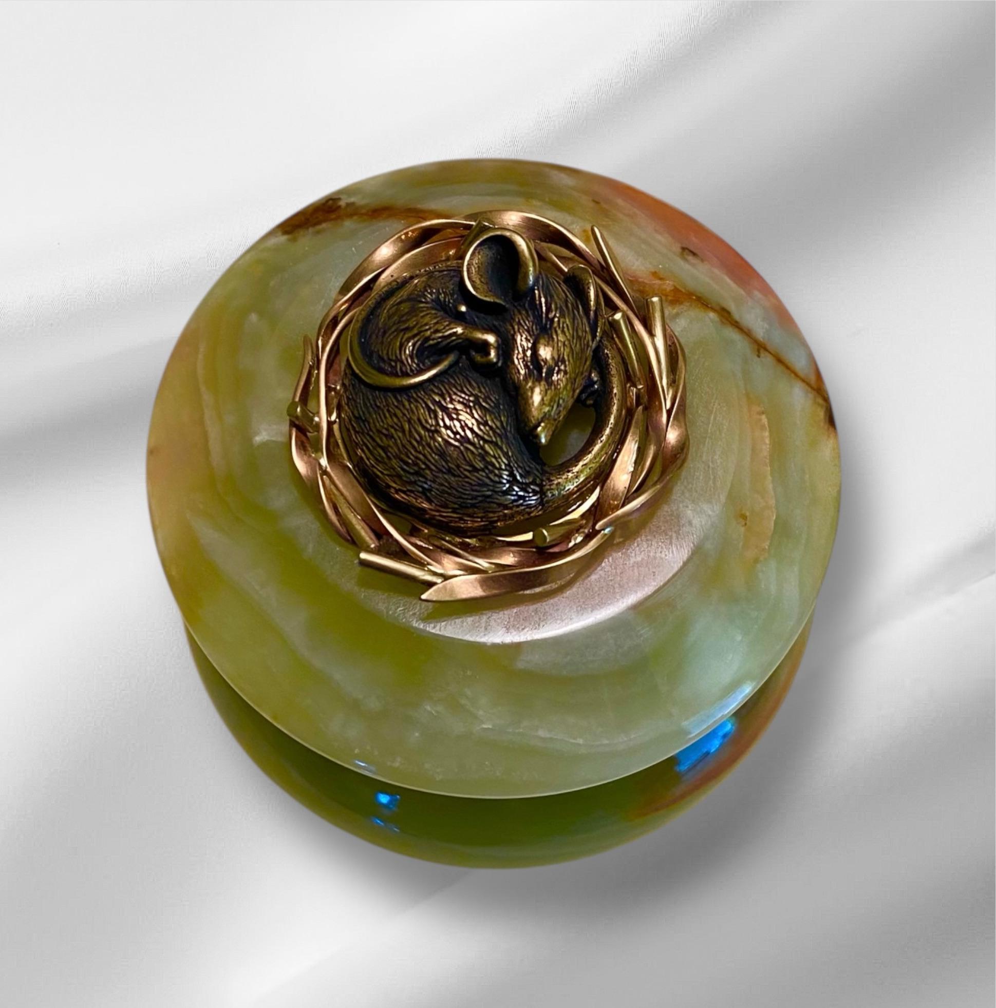 A sleeping dormouse tops a green onyx ring box.  The mouse measures one inch and is sensitively sculpted in bronze.  He naps in a nest fabricated from rose and yellow gold.  The composition is mounted on a Victorian era green onyx box.  The antique