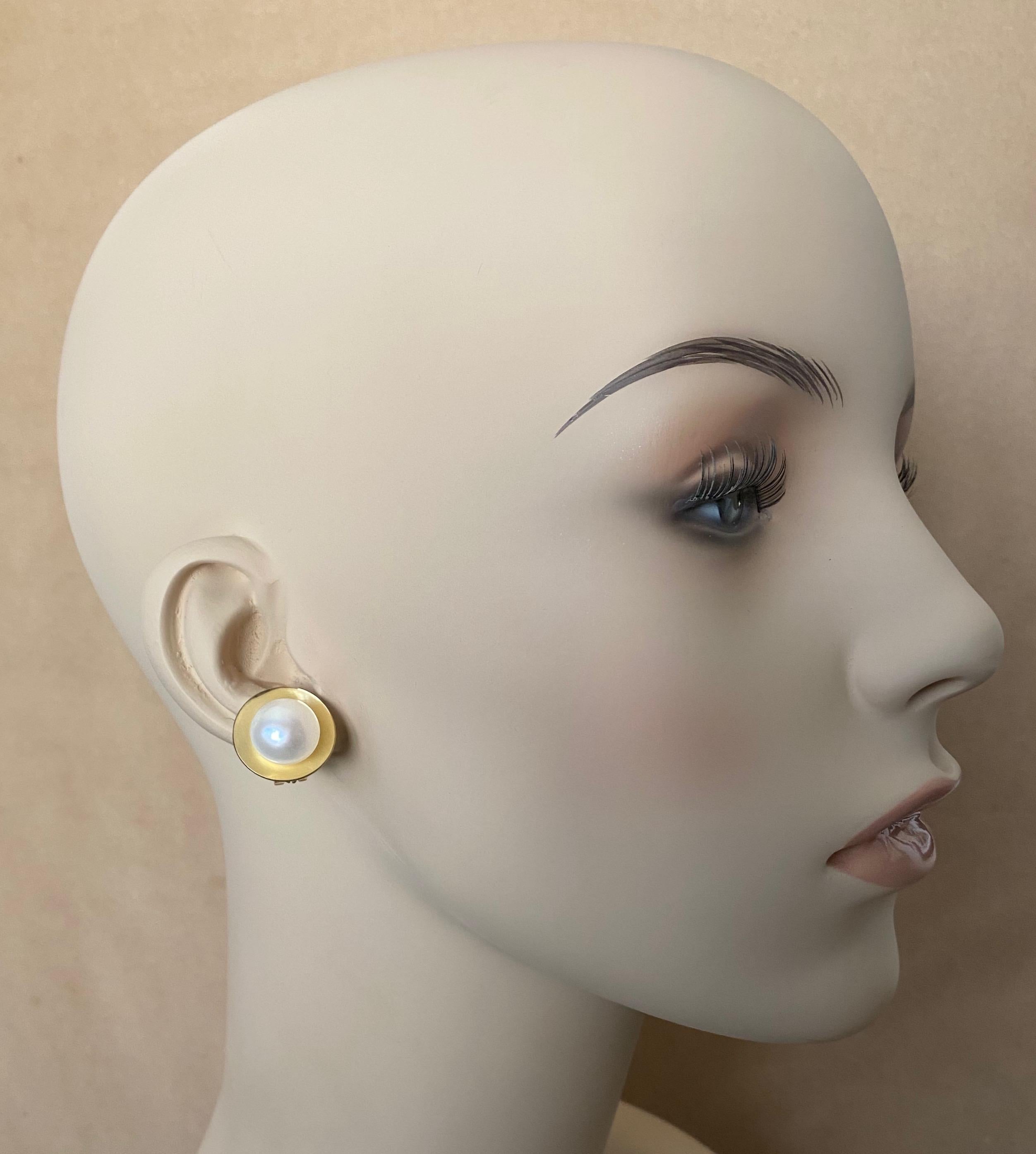 13mm bright white button pearls are featured in these 18k gold earrings.  The pearls possess wonderful luster and are blemish free.  The pearls are set within highly polished convex disks that reflect the pearl, creating a satin appearance.  The