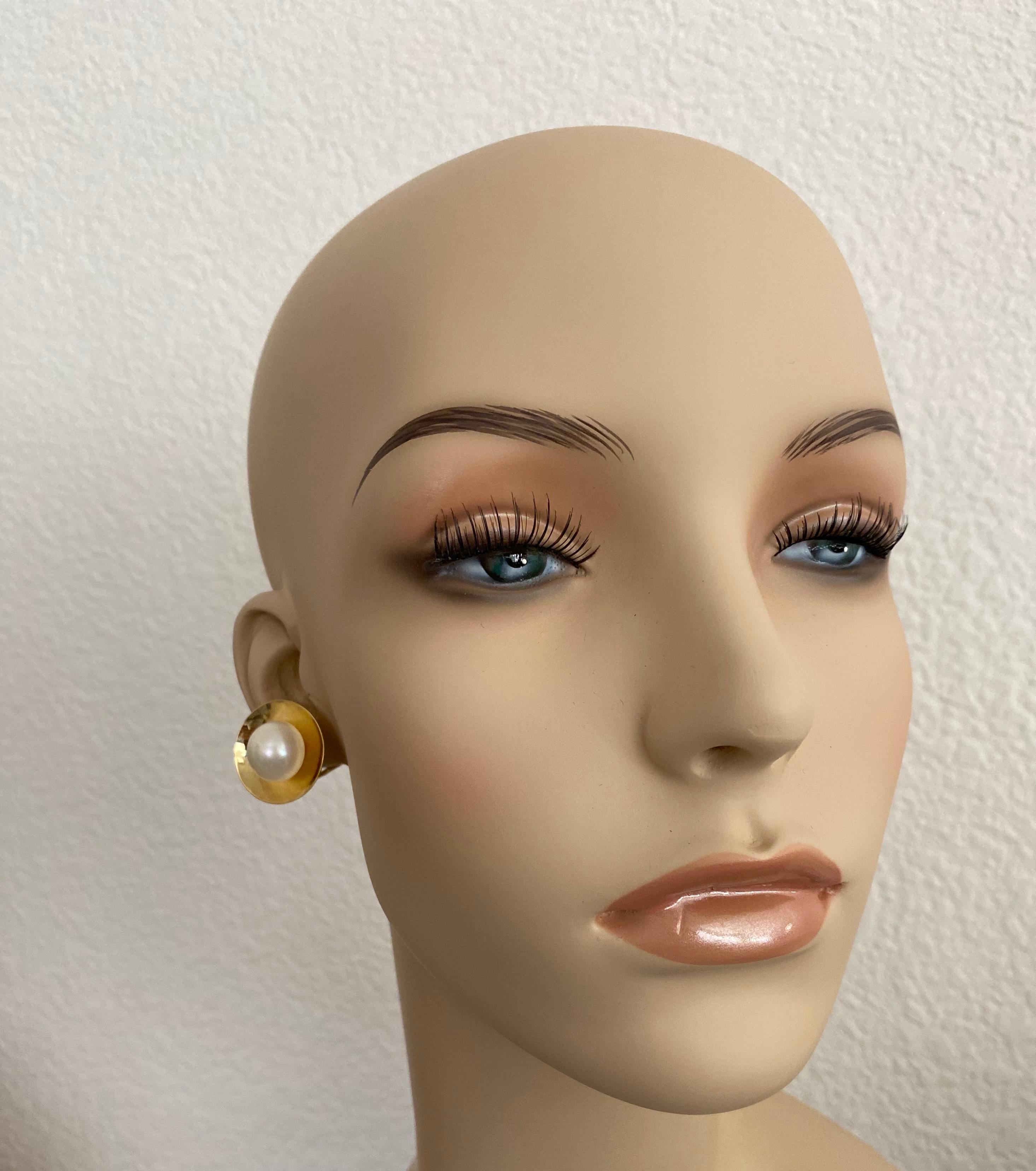 14 mm große, strahlend weiße Knopfperlen zieren diese klassischen Ohrringe aus 18 Karat Gelbgold.  Die Perlen besitzen einen wunderbaren Glanz und sind frei von Fehlern.  Die Perlen sind in konvexe Scheiben gefasst, die die Perle reflektieren und