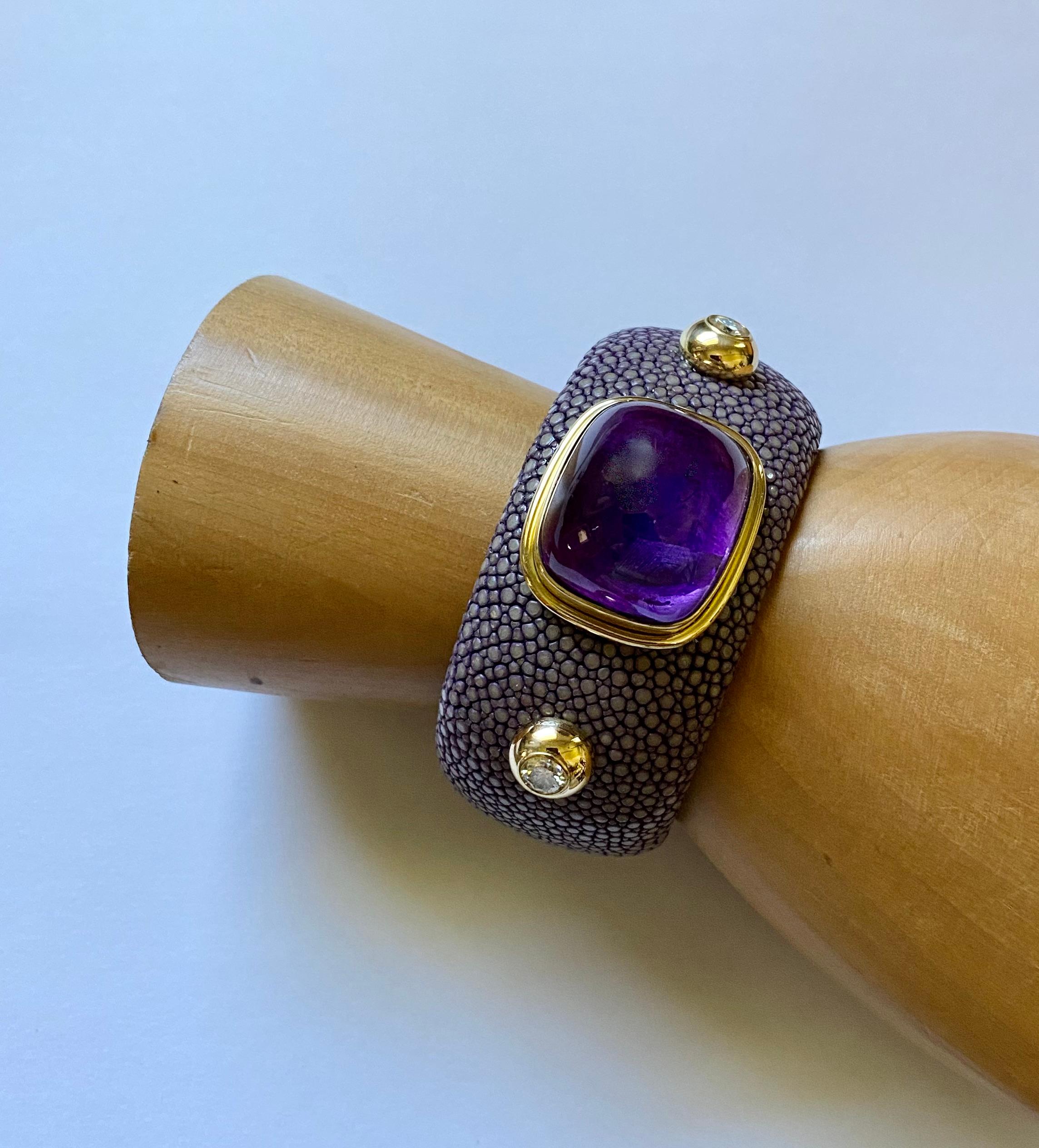 Cabochon amethyst is the centerpiece of this dramatic cuff bracelet.  The amethyst (origin: Brazil) weighs 36.70 carats.  The gem is cut as a high cushion shape dome, and is well polished.  It is set within an 18k yellow gold bezel.  Flanking the