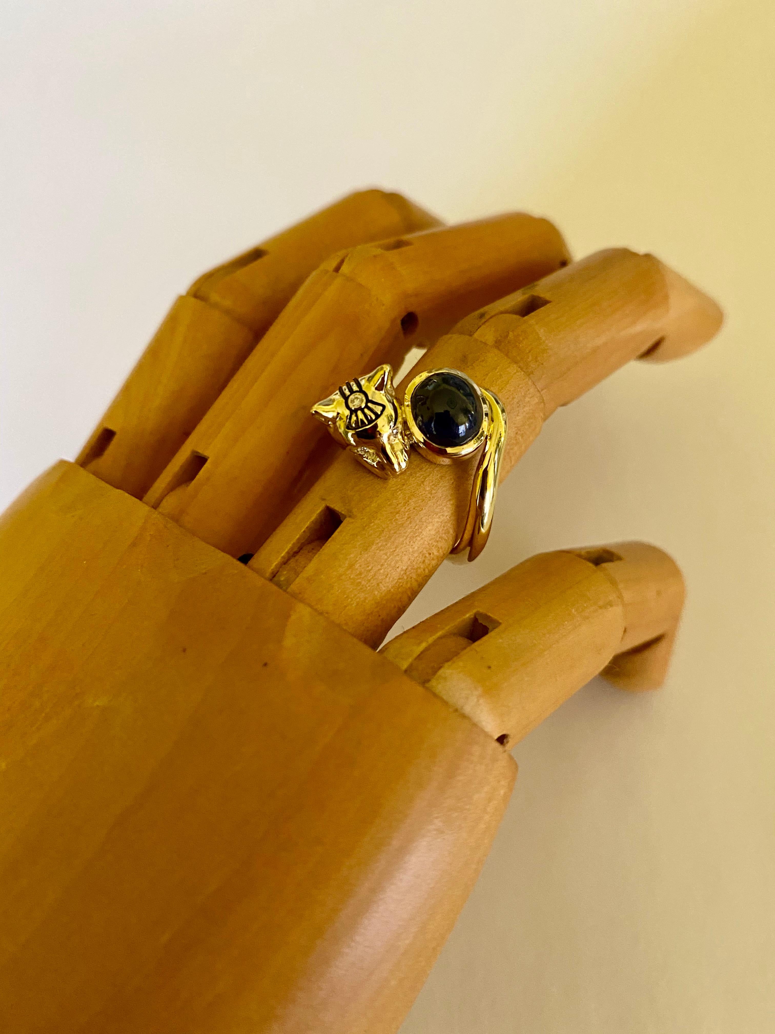Cabochon blue sapphire and diamonds lend prominence to this Egyptian Revival cat ring.  Bastet, also known a Bast, is a fierce Egyptian goddess worshiped in the form of a lion and later, after is domestication, a cat.  This 18k gold wearable