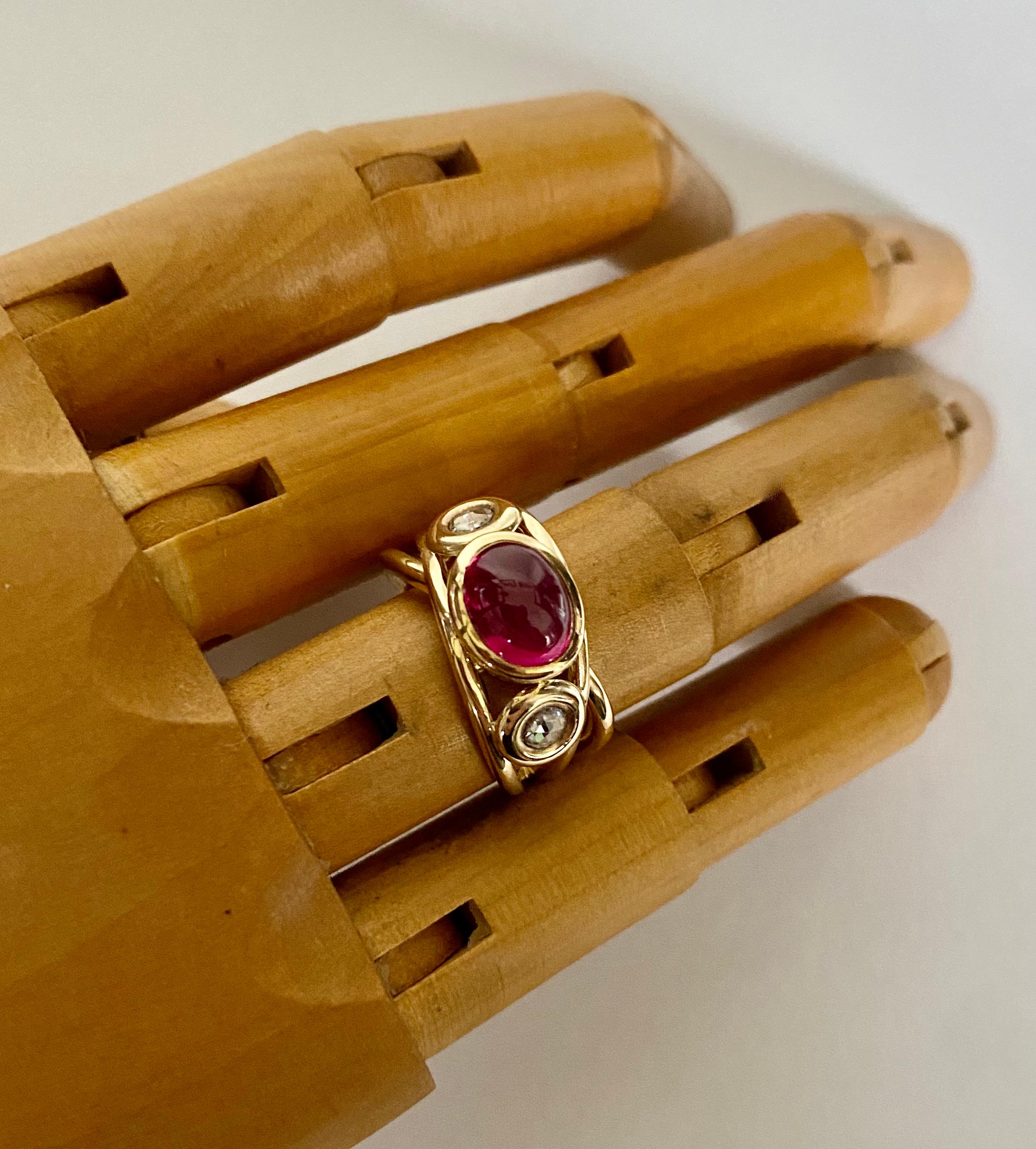 Cabochon ruby is featured in this open band ring.  The ruby possesses optimum color.  It is well cut and polished.  The gem also contains a surprise-a baby six point star.  The ruby is flanked by two rose cut diamonds. The hand fabricated 18k gold