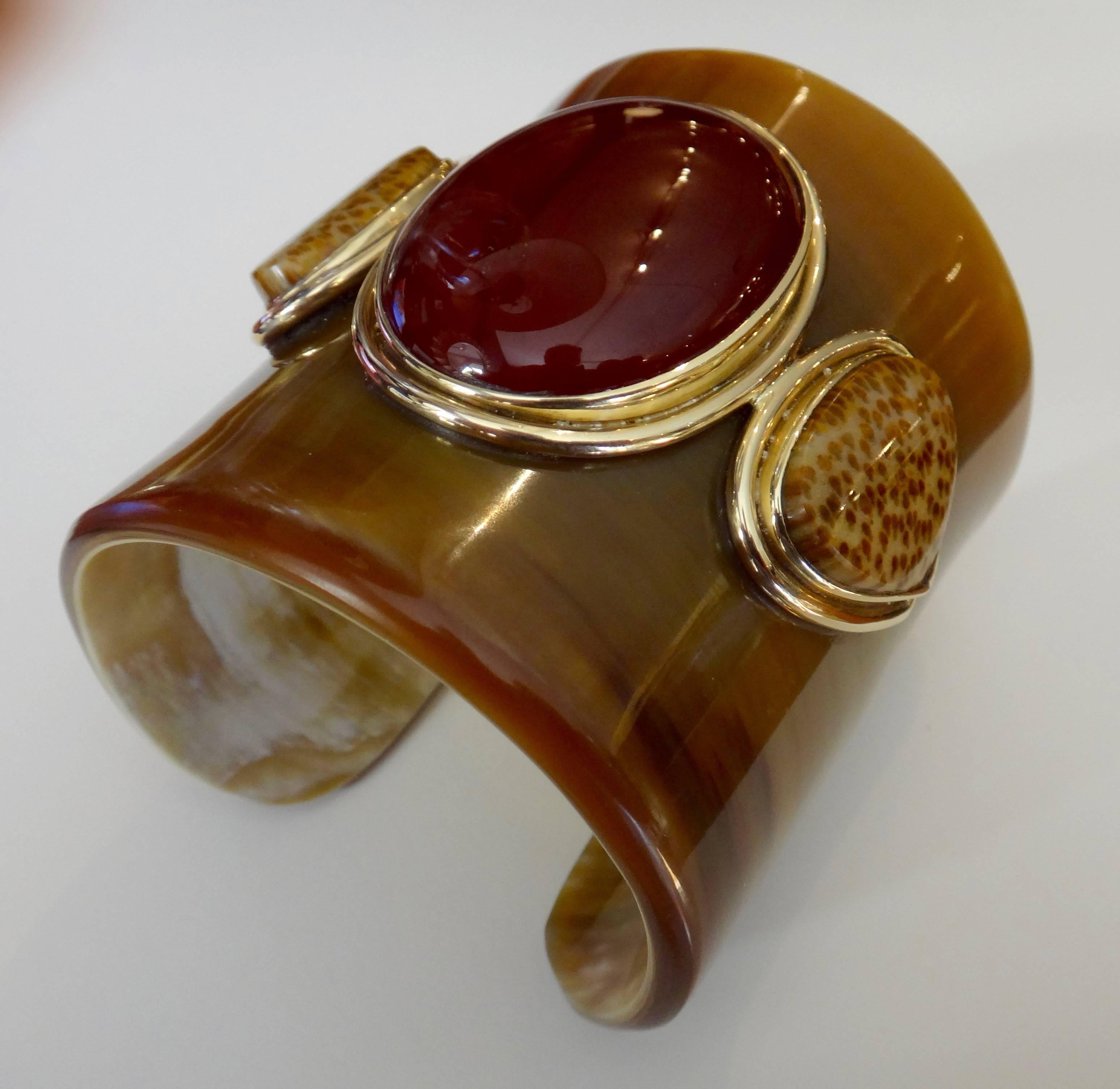 A massive cabochon of carnelian is flanked by a perfectly matched pair of petrified palm wood cabochons in this totally cool cuff bracelet.  The gems are mounted in a hand fabricated 18k yellow gold setting which have been mounted on an Ankole horn