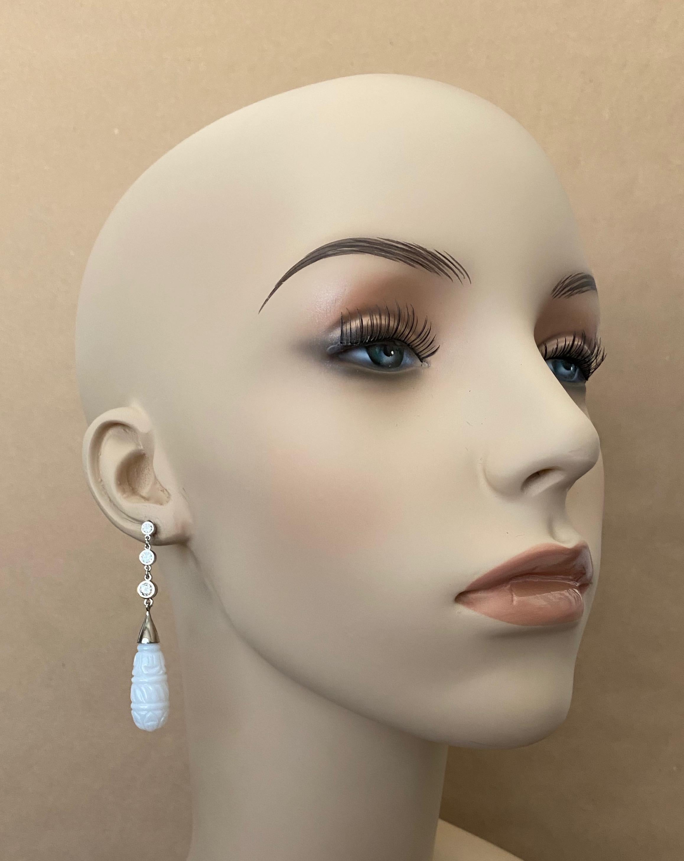 Three bezel set white diamonds in graduated sizes from smaller to larger support beautifully carved white chalcedony drops in these elegant dangle earrings.  The drops were exquisitely carved and polished in exotic India.  The design for these chic