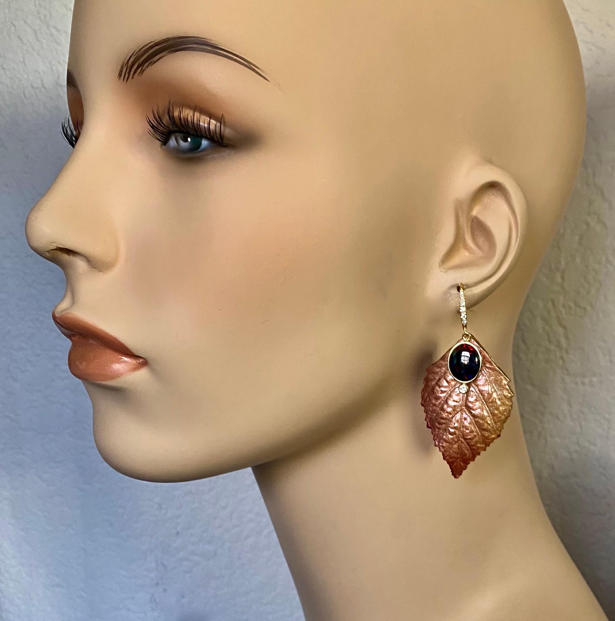 Ethiopian black opals along with diamonds form a harmonious composition in these elegant dangle earrings.  The opals are well matched and polished.  They have a black base with intense flashes in the full spectrum of colors.  The gems are mounted on