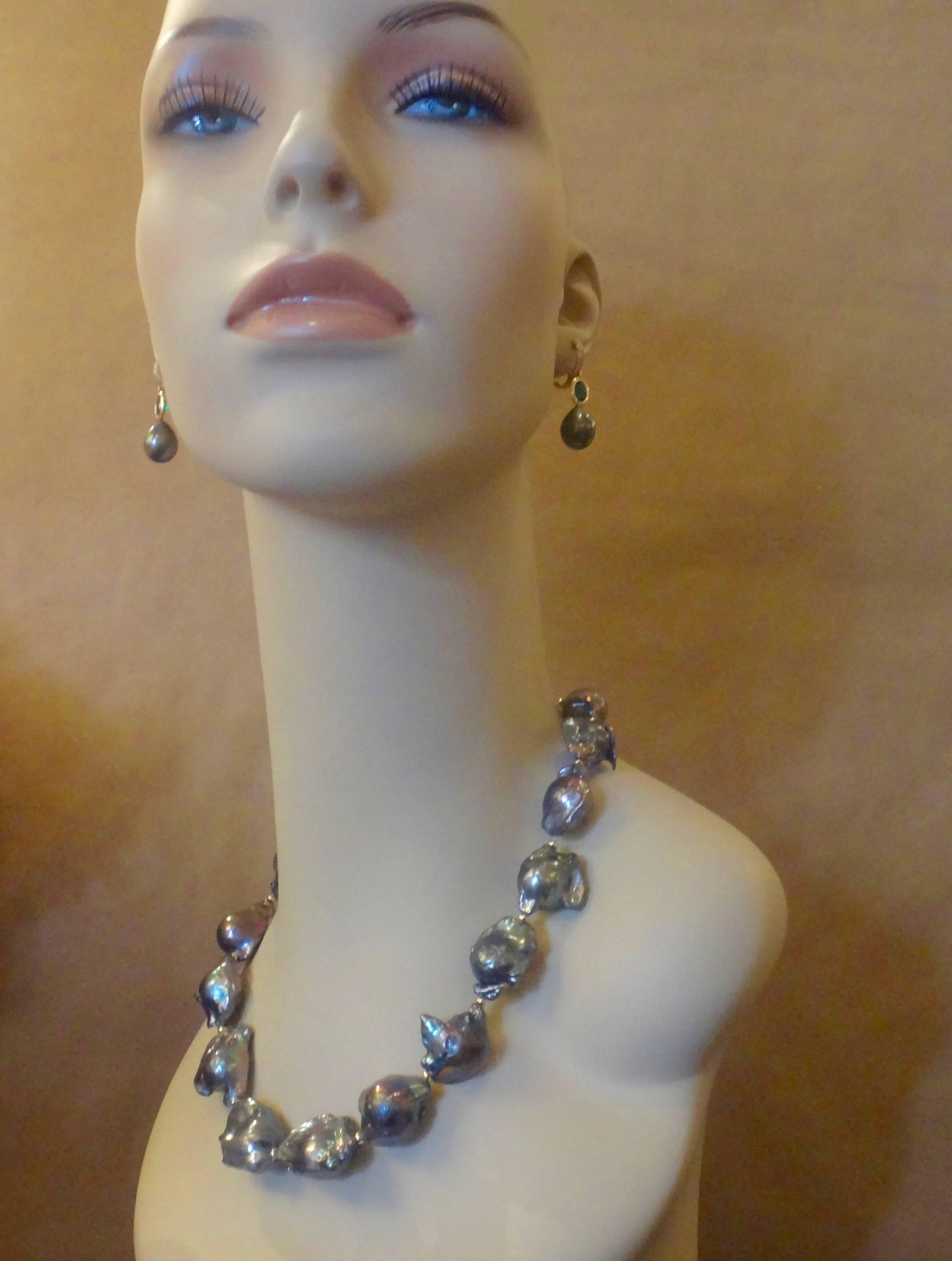 Sixteen very baroque dark gray cultured pearls form this bold necklace.  The rich base color of the pearls reflects shades and tones of pinks, blues and greens.  The pearls are spaced with small gold beads. The  necklace is finished with a vermeil