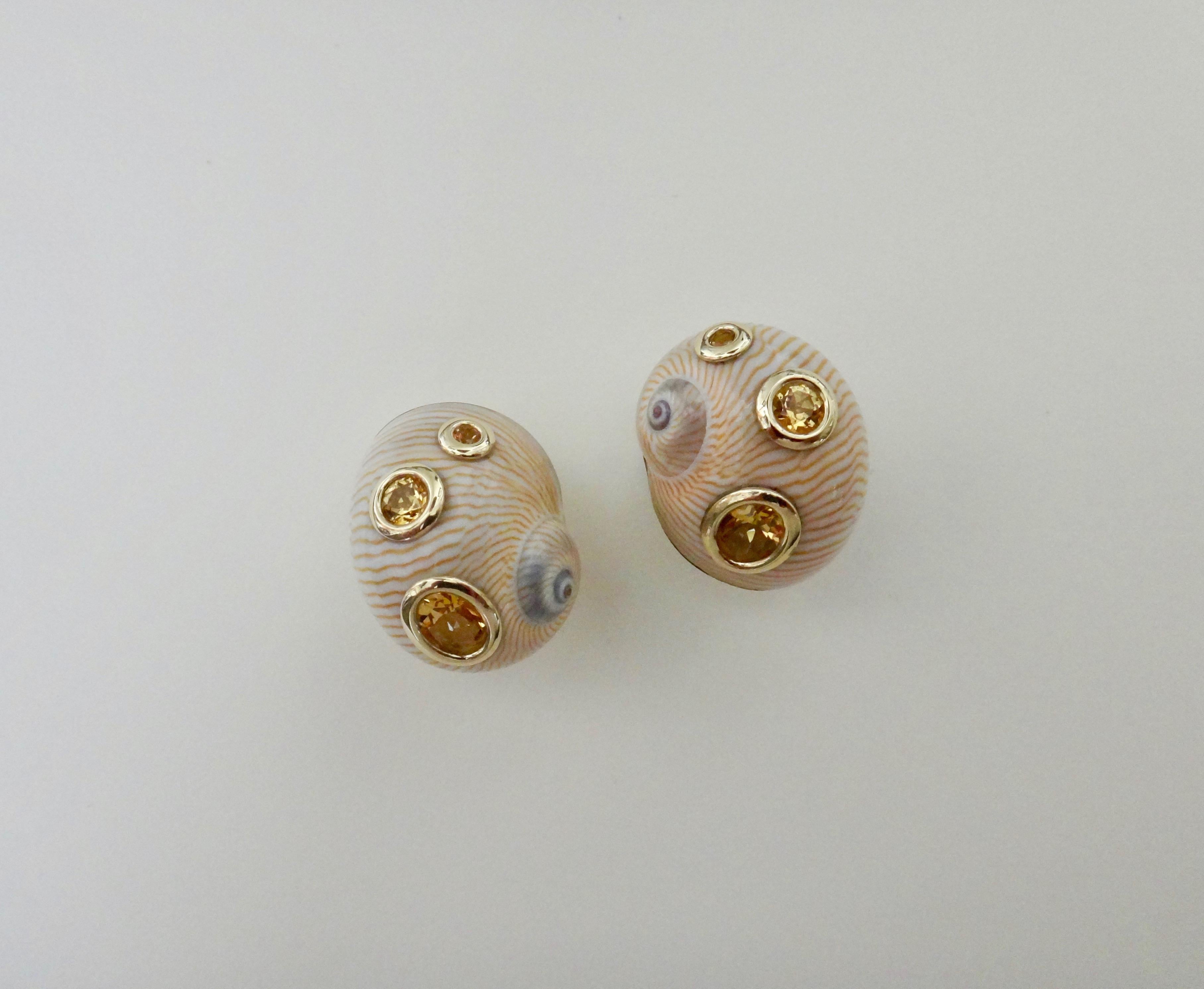 Natural olive shells create the foundations for these button earrings.  The highly polished cream and tawny colored shells have been studded with bezel set golden topaz in round and oval shapes.  The earrings are backed in 18K yellow gold and come