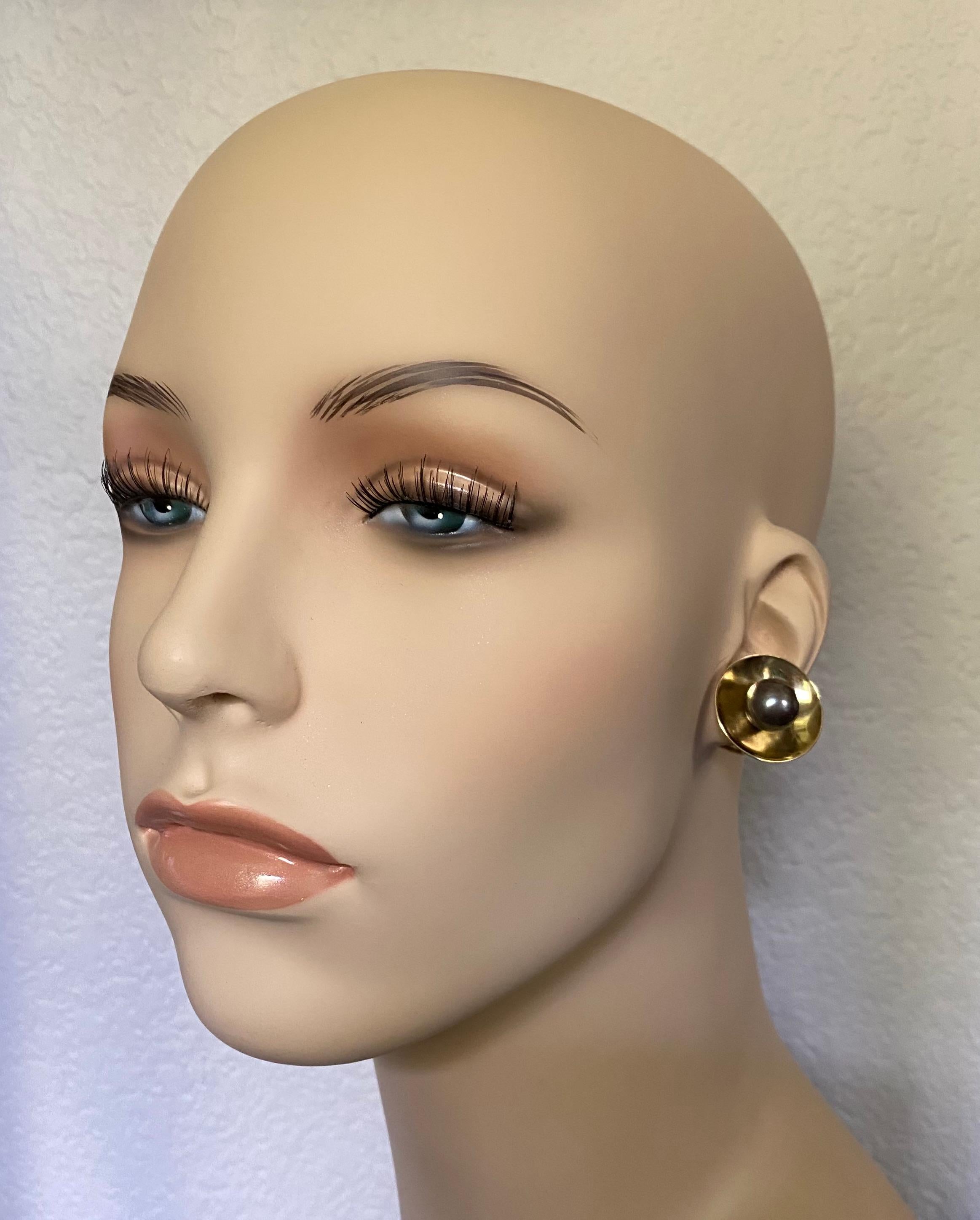 11mm medium gray Tahitian pearls are showcased in these classic 18k yellow gold button earrings.  The gem quality pearls are blemish free and possess a rich luster.  The pearls are set within concave disks that reflect the pearl color and thus
