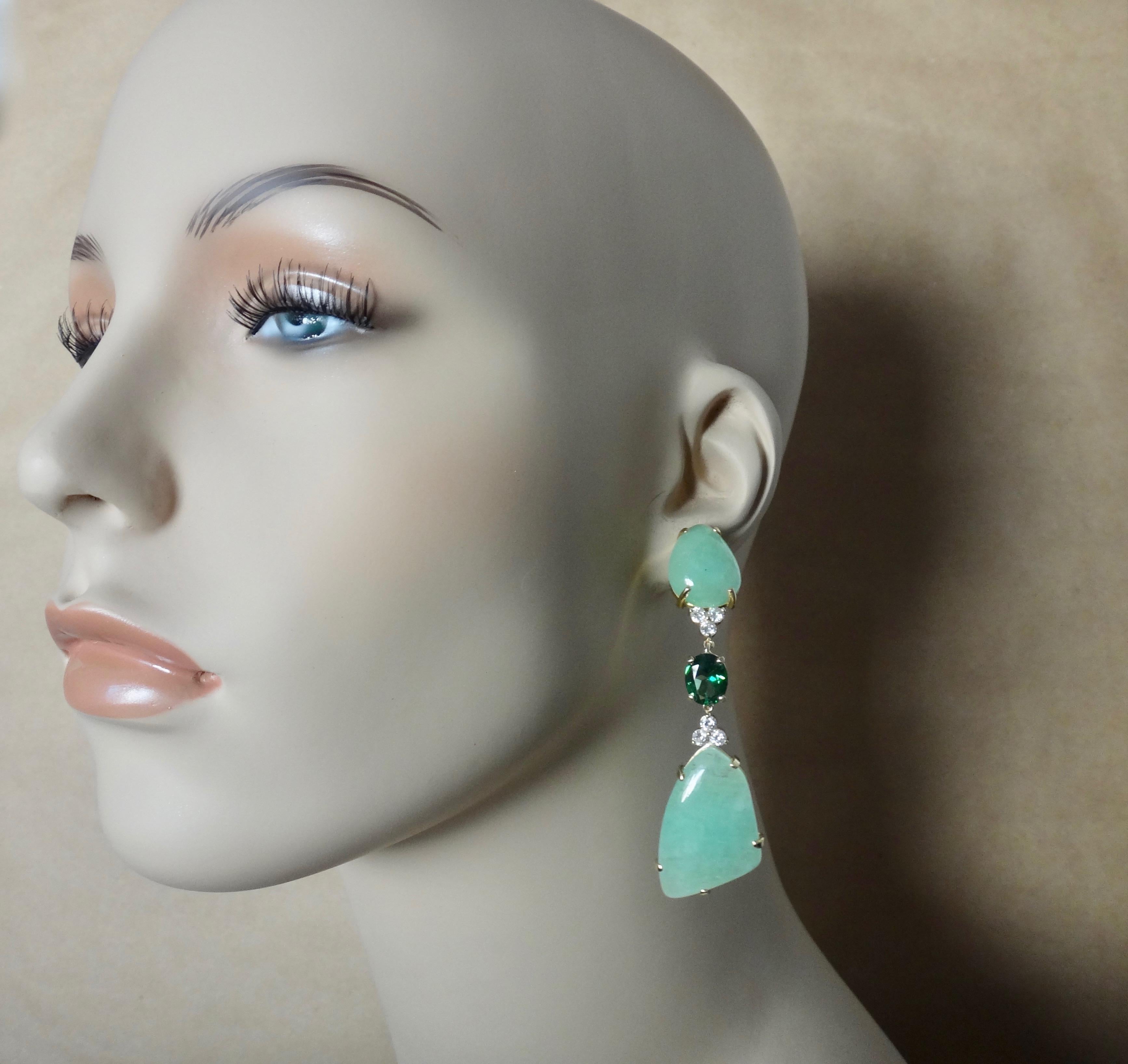 Free-form cabochons of green beryl (origin: Brazil) are perfectly book matched in these dramatic dangle earrings.  Beryl is a large family of gems.  Well known members include emerald and aquamarine.  Lesser known but equally beautiful members are