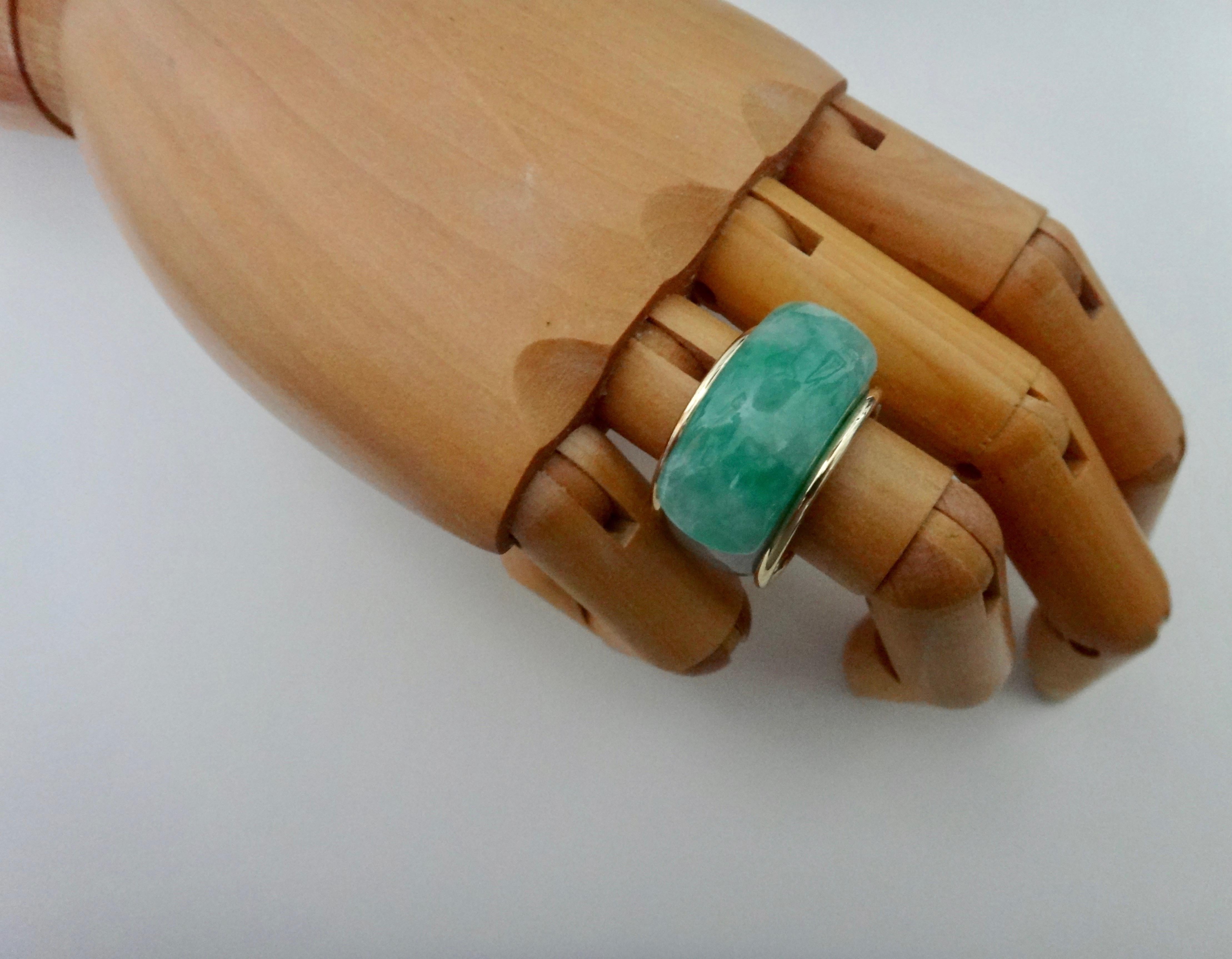 Jadeite (origin: Myanmar) has been carved into a classic saddle ring.  The Asian saddle ring is a style hundreds of years old.  The carver oriented the rough in such a way so that the 