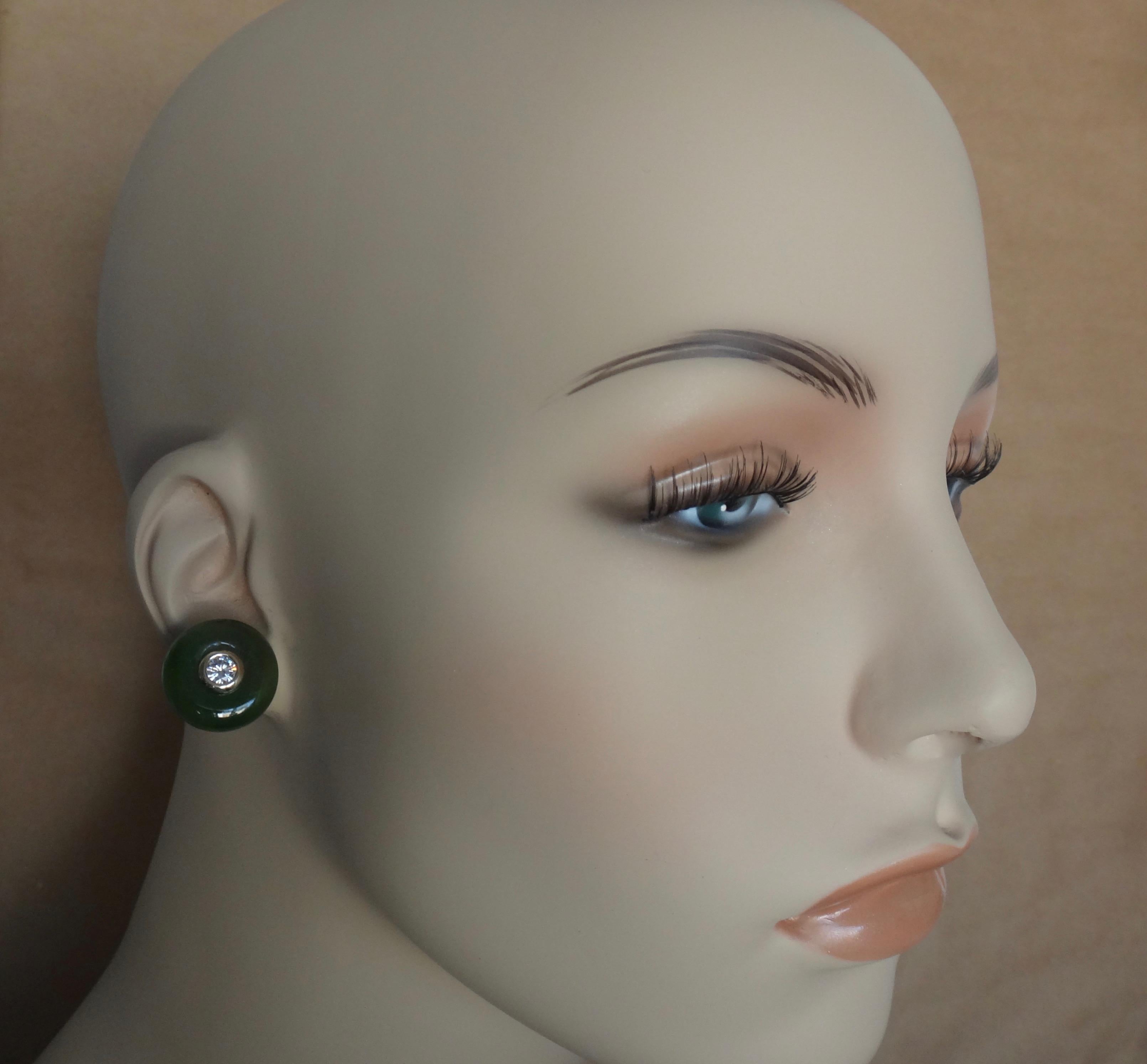 Jadeite discs (origin: Myanmar) in modeled shades of green are embellished with bezel set, brilliant cut white diamonds.  The jadeite possesses a glassy polish typical of the material.  The earrings have 18k posts with omega clip backs for comfort