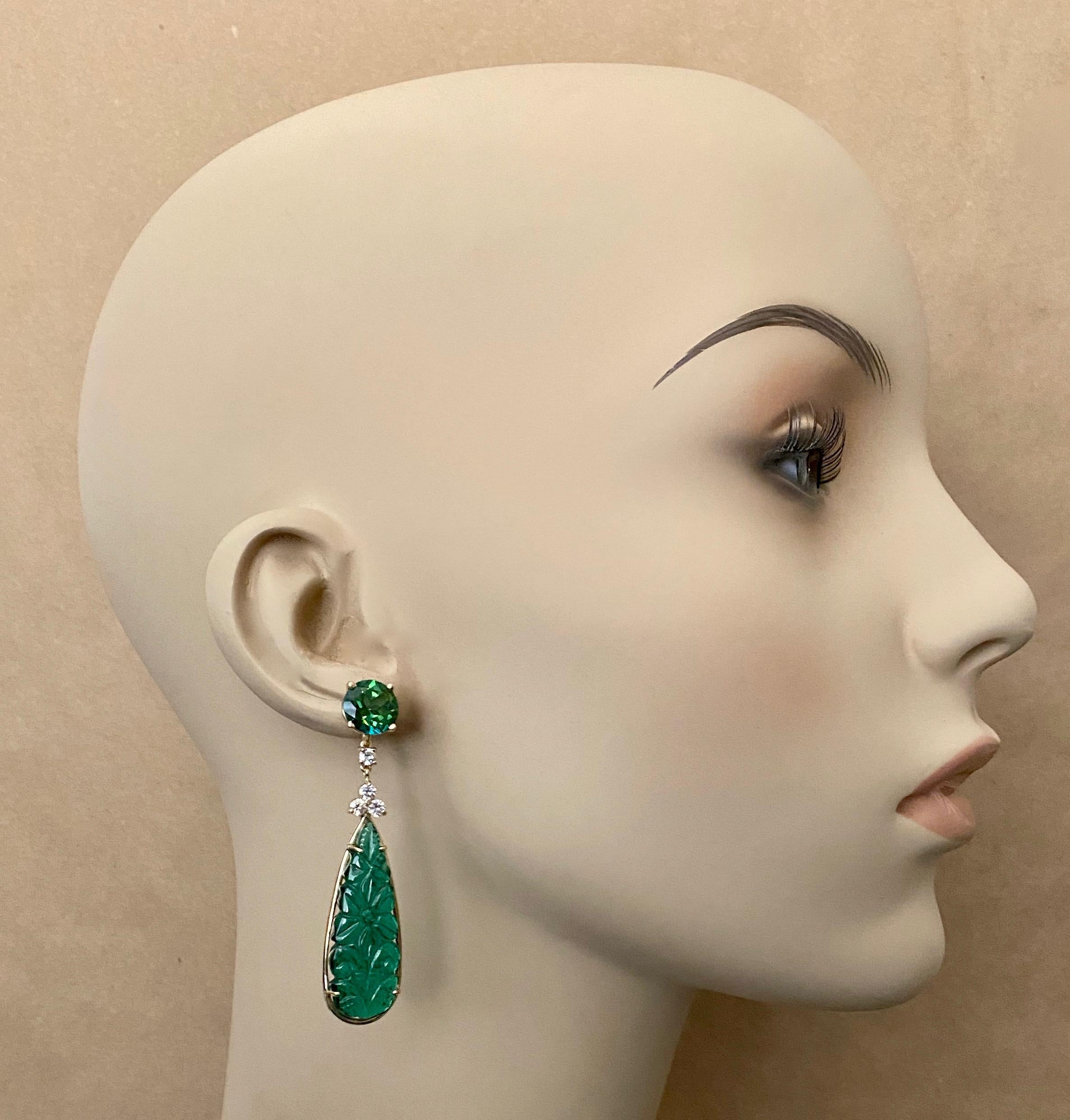 Green onyx drops are featured in these elegant dangle earrings.  The onyx (origin: Peru) is translucent, brilliant green and finely carved in a floral design in the Indian style.  The drops are complimented by bright green, flashy and brilliant cut