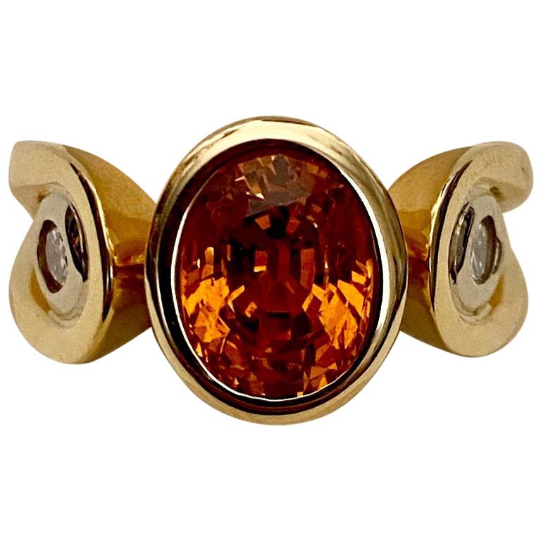 Hessonite garnet is featured in this unique three stone ring.  Hessonite is a variety of grossular garnet.  Though most grossular garnets are green, hessonite is coveted for it's rich cinnamon color.  Origin: Sri Lanka.  The bezel set gem is