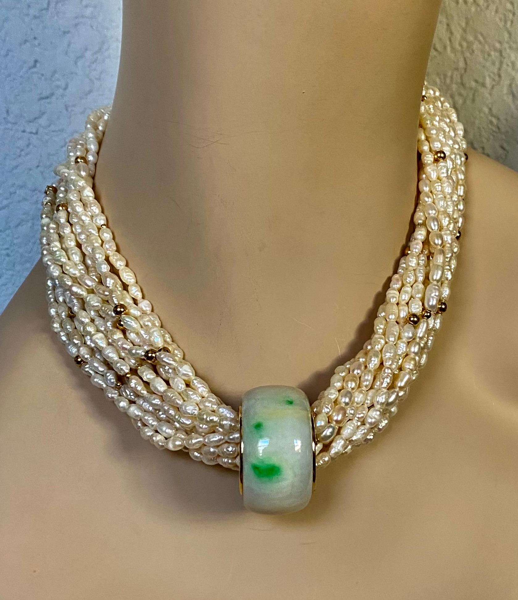 A jadeite archers ring is suspended from a multi-strand torsade in this elegant necklace.  The white jadeite has random spots of green, what the Chinese describe as 