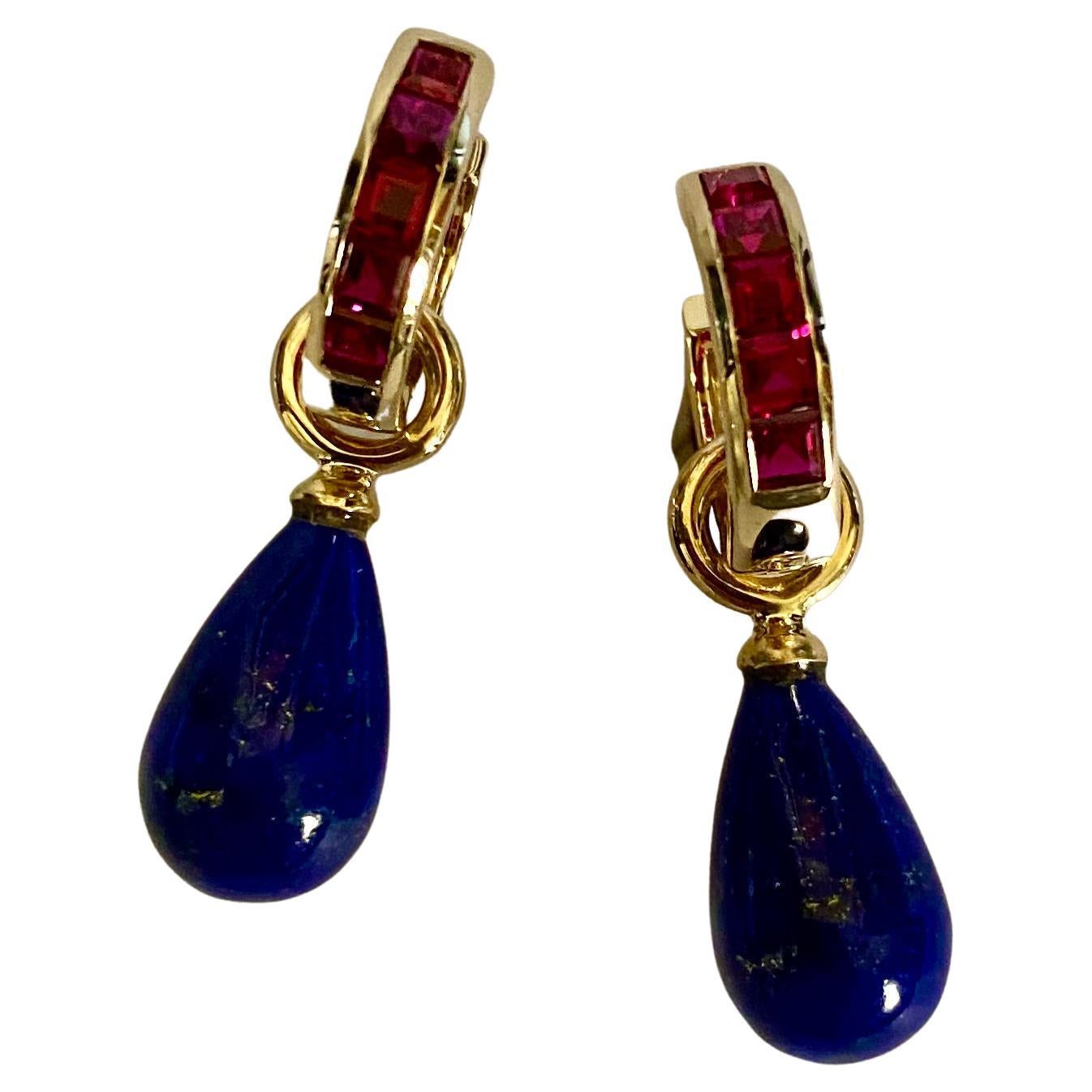 Lapis Lazuli are featured in these sophisticated drop earrings.  The lapis have beautiful golden flecks, are well cut and polished to a mirror like finish.  They dangle from huggie style hoops channel set with bright red rubies.  The drops are