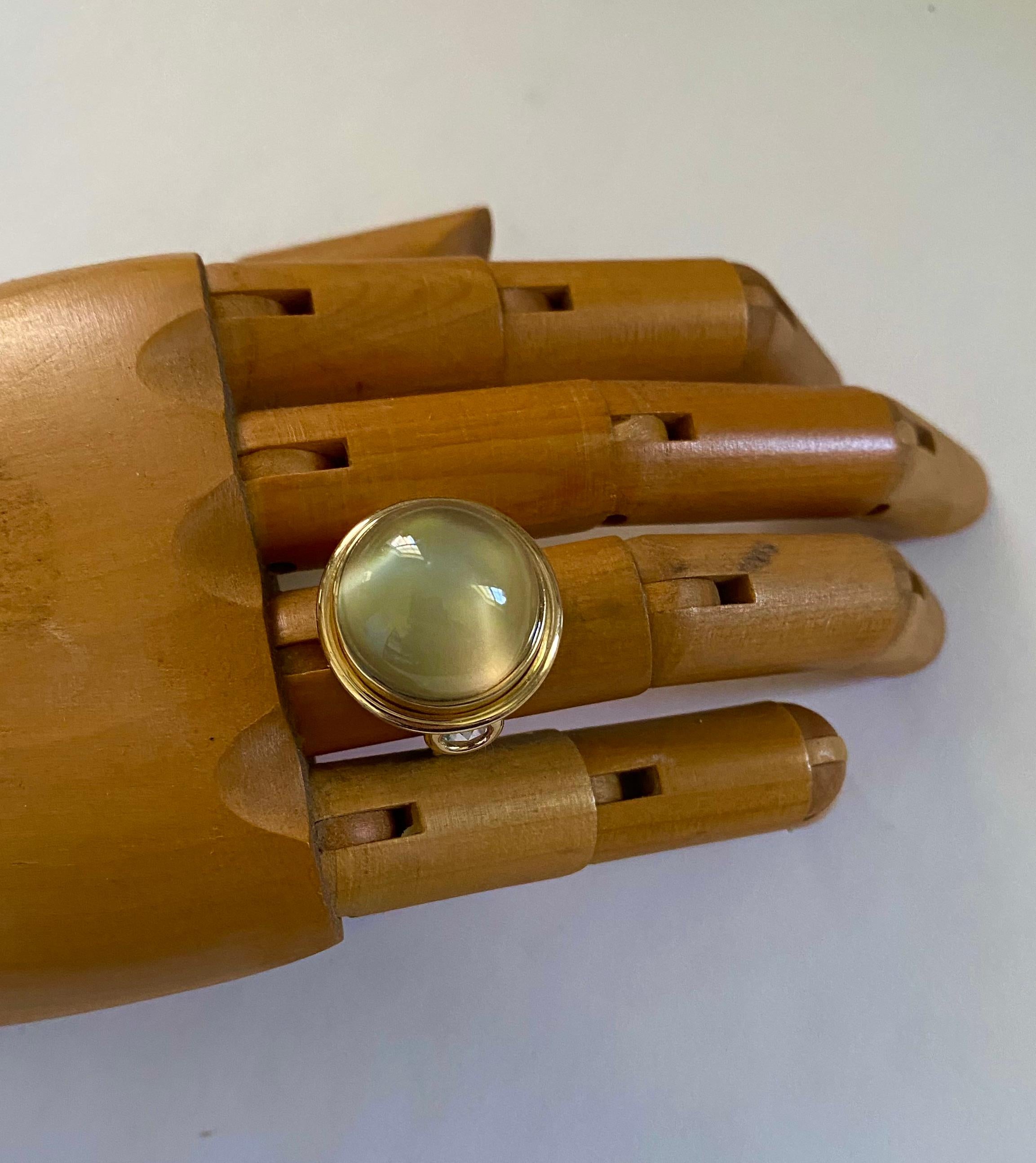 Moonstone is featured in this simple, elegant cocktail ring.  The moonstone (origin: Sri Lanka) weighs 23.6 carats.  The gem is a delicate greenish gray color and has been cut in a high dome round cabochon shape with excellent polish.  It is set
