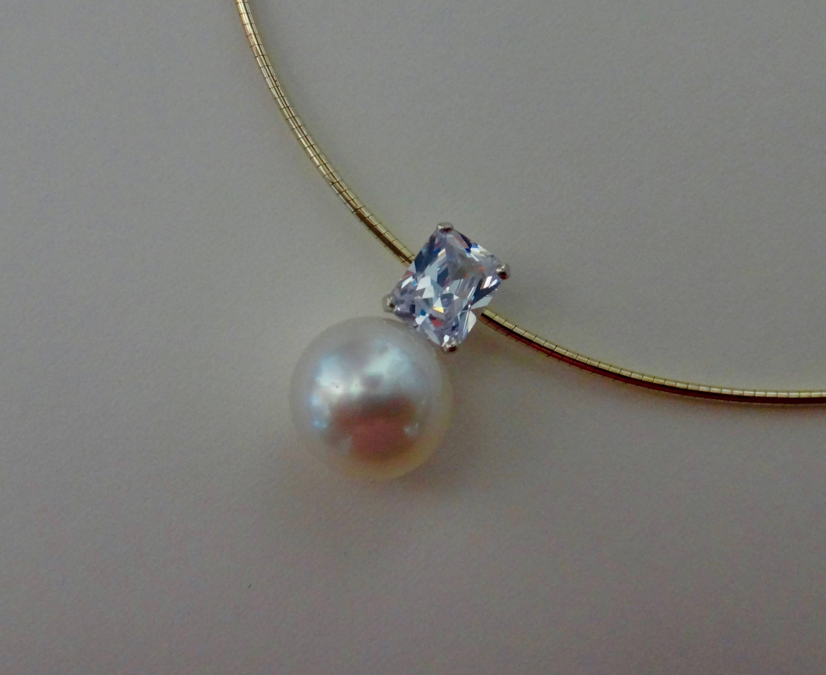 A 15mm, gem quality Paspaley South Seas pearl is paired with a radiant cut silver sapphire in this classic and readily wearable pendant.  The pearl possesses a flawless finish and brilliant white color.  The sapphire is colorless and exceptionally