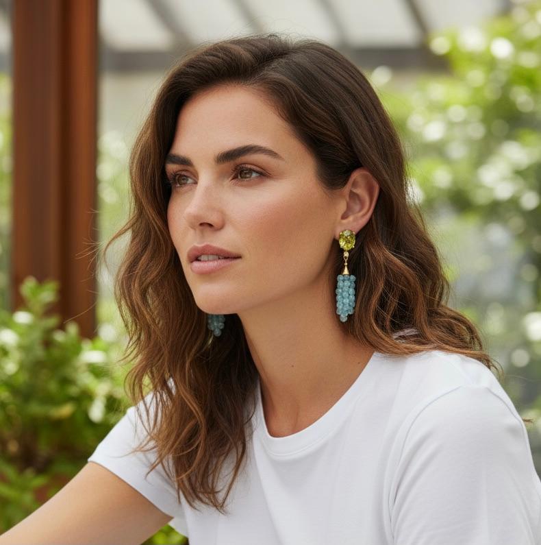 I toni freddi del blu e del verde definiscono questi stravaganti orecchini pendenti.  I peridoti di forma ovale (origine: Arizona) sono molto appariscenti, ben tagliati e perfettamente abbinati.  Le minuscole bricole di topazio blu sono state