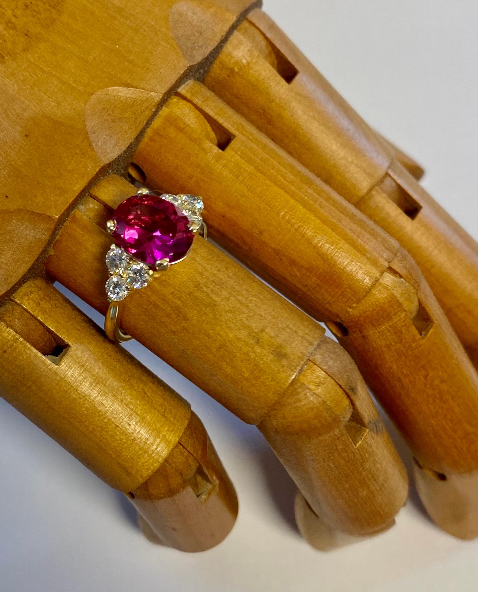 A pink ruby is featured in this elegant and classic cocktail ring.  The ruby (origin: Sri Lanka) is a lively and intense pinkish-red color.  The gem is well cut and polished.  The ruby is flanked by three white brilliant cut diamonds set in a