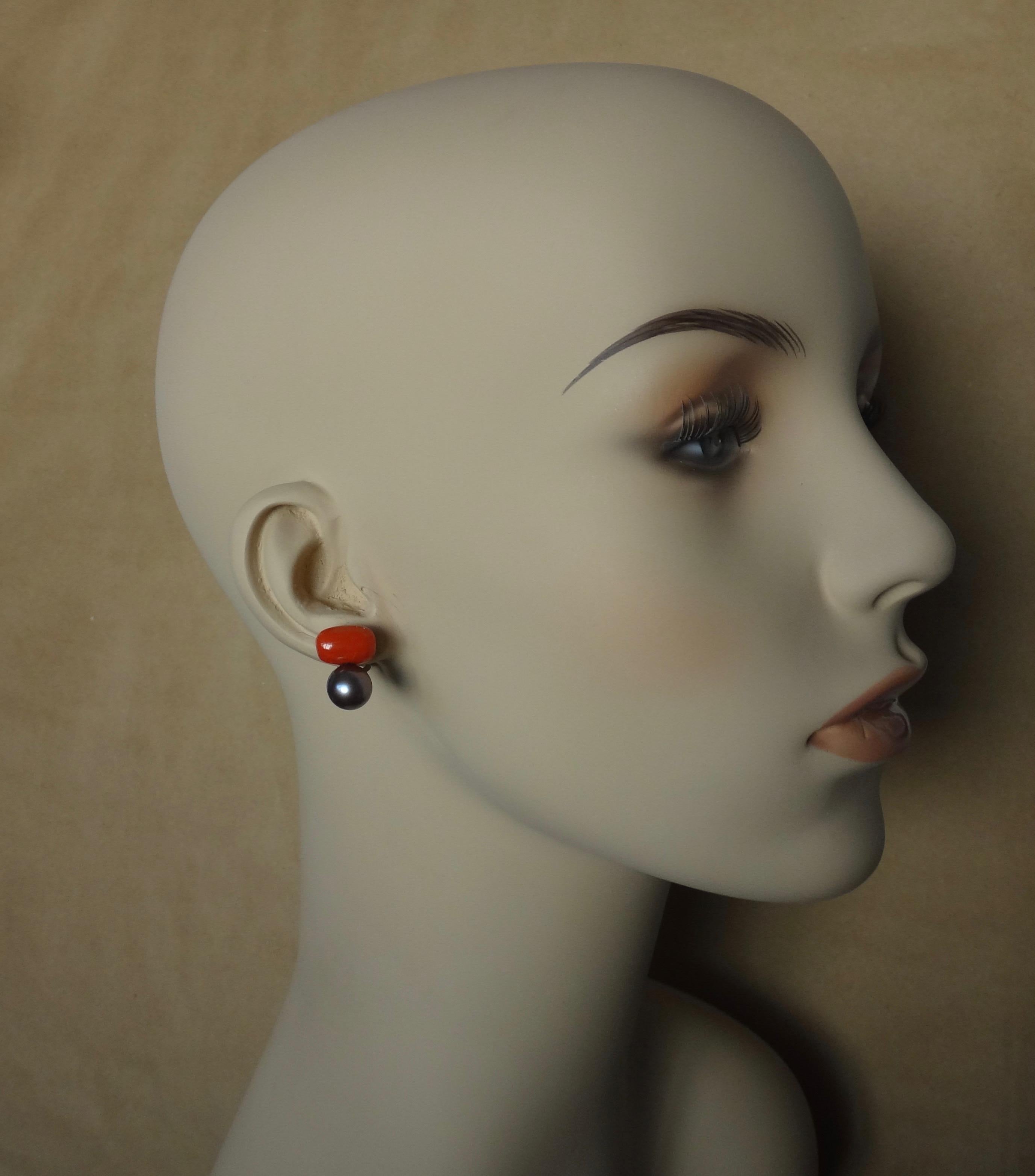 A beautifully matched pair of Mediterranean red corals are featured in these two stone, stud earrings.  The coral are a rich tomato red color and are highly polished.  Complimenting those gems are a pair of dark gray Tahitian pearls which possess