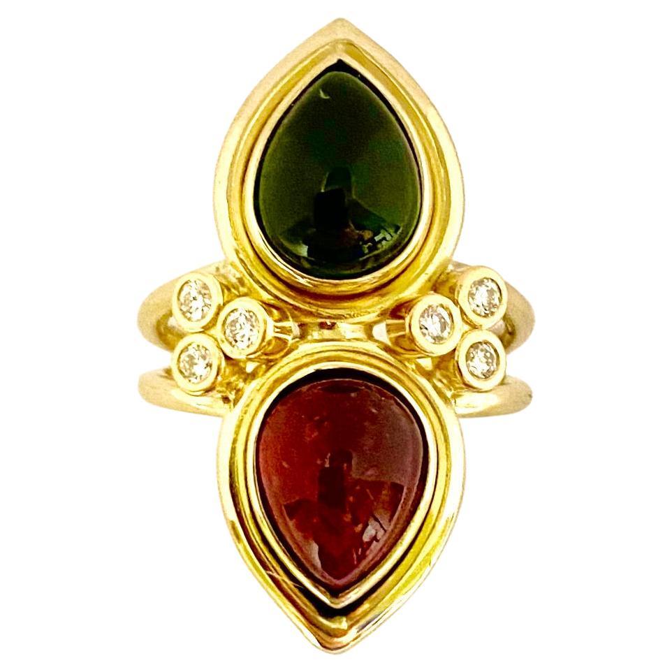 Rote und grüne Turmaline sind in diesem Ring mit zwei Steinen zu sehen.  Die birnenförmigen Edelsteine (Herkunft: Brasilien) sind intensiv gefärbt und in ihrer Form perfekt aufeinander abgestimmt.  Die in der Lünette gefassten Turmaline werden durch