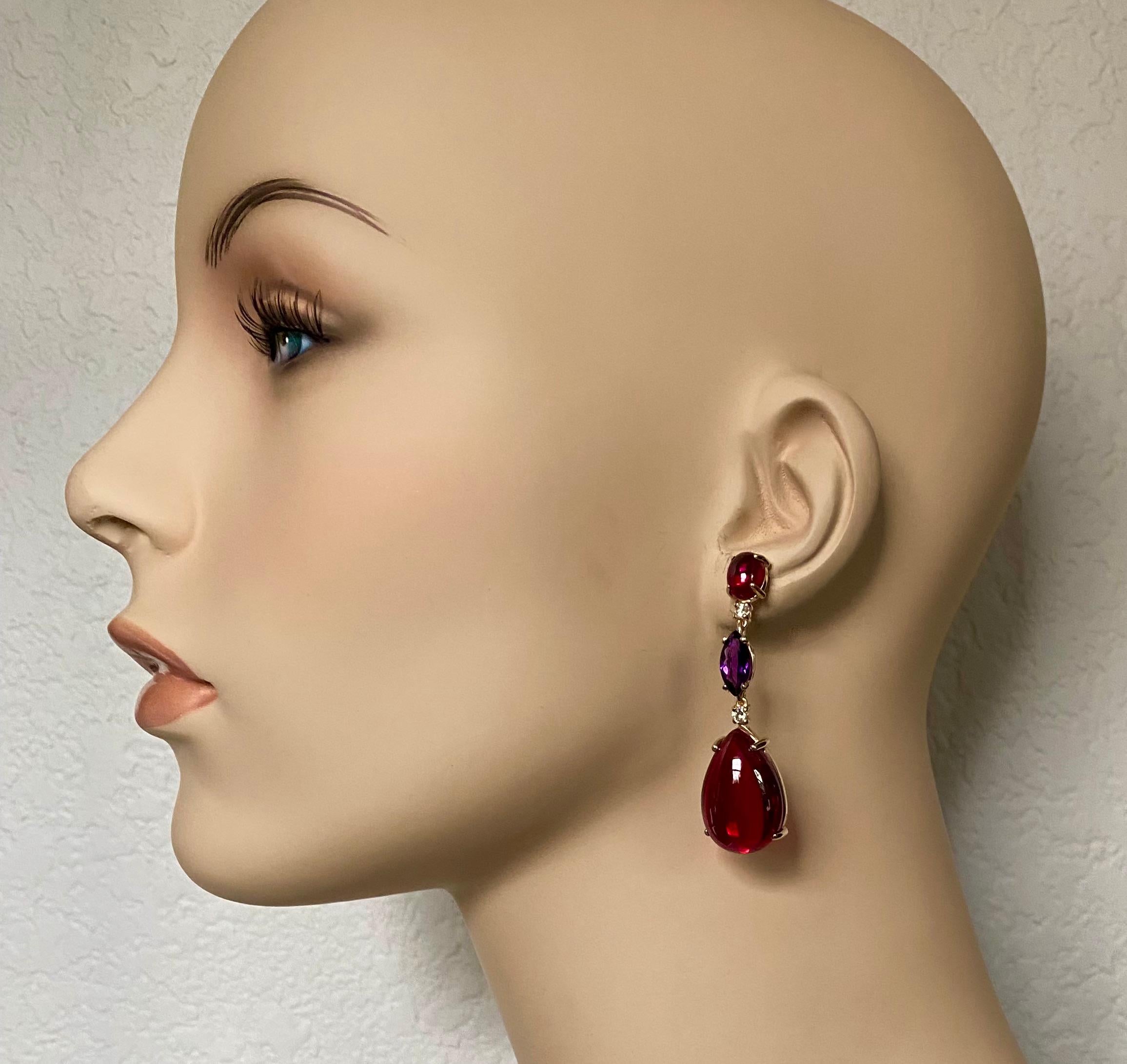 Red and purple colors glow in these statement dangle earrings.  Brightly colored cabochon rhodolite garnet (origin: Tanzania) is complimented by richly colored marquise cut amethyst (origin: Brazil).  The gems support cabochon red topaz (origin: