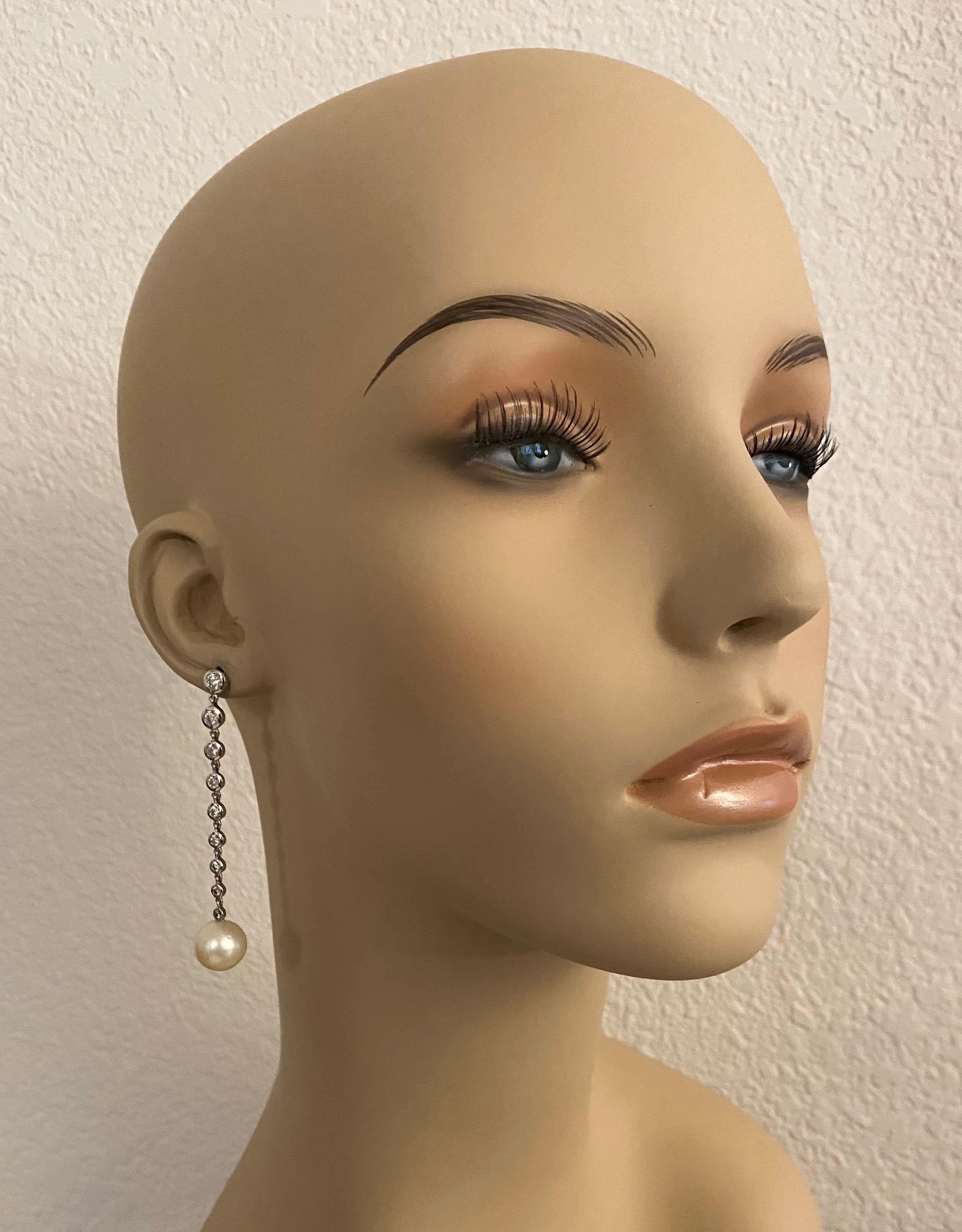 South Seas pearls and diamonds constitute these chic dangle earrings.  The pearls (origin: Australia) measure 12mm, are creamy white and possess rich luster.  Eighteen diamonds are bezel set in white gold, graduated in size, are VVS clarity and F