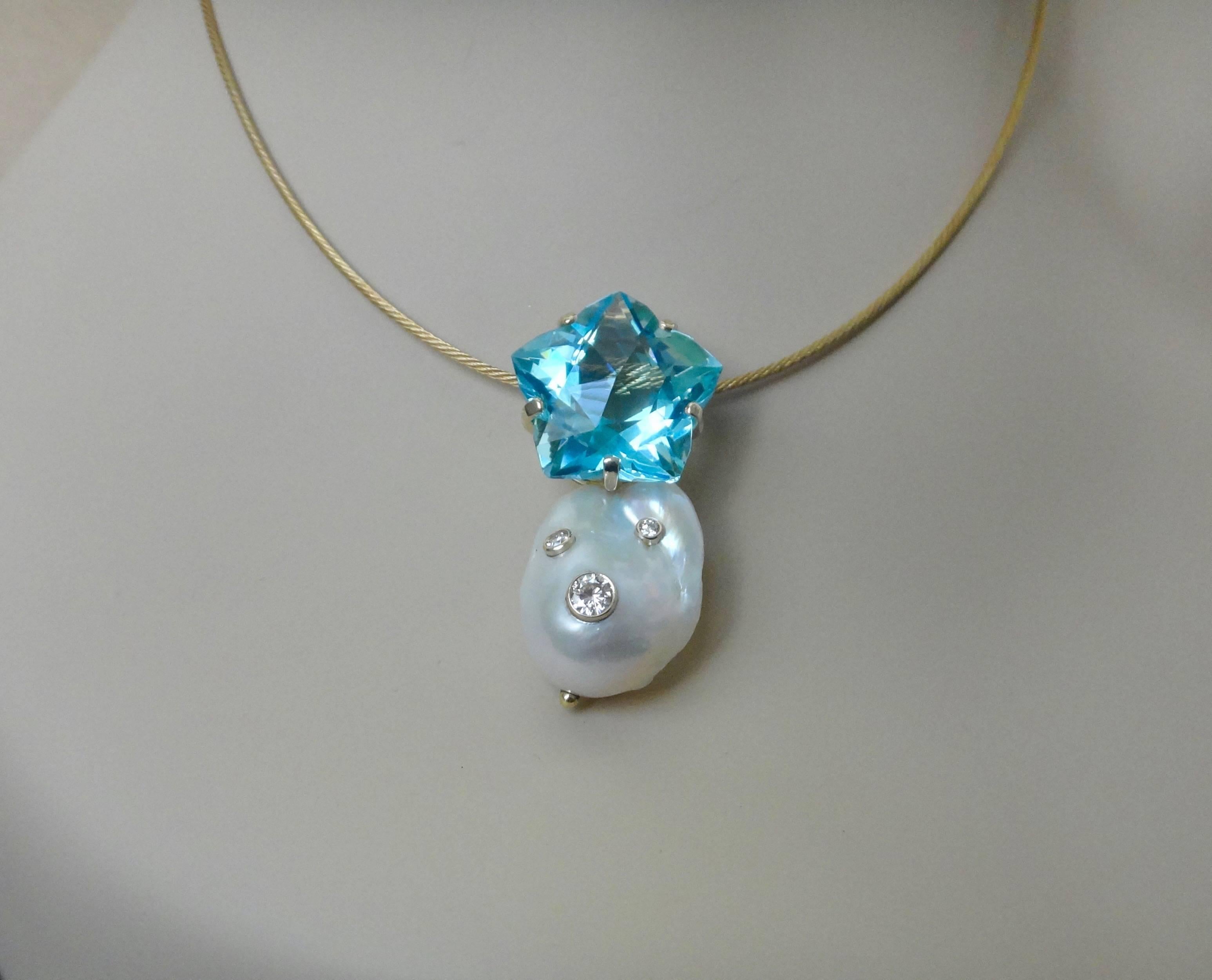 A uniquely cut blue topaz is the star of this pendant.  The bright, aquamarine blue gem is expertly shaped and weighs 19.85 carats.  It is complimented with an exquisite white cloud pearl that has been drilled and decorated with three brilliant cut