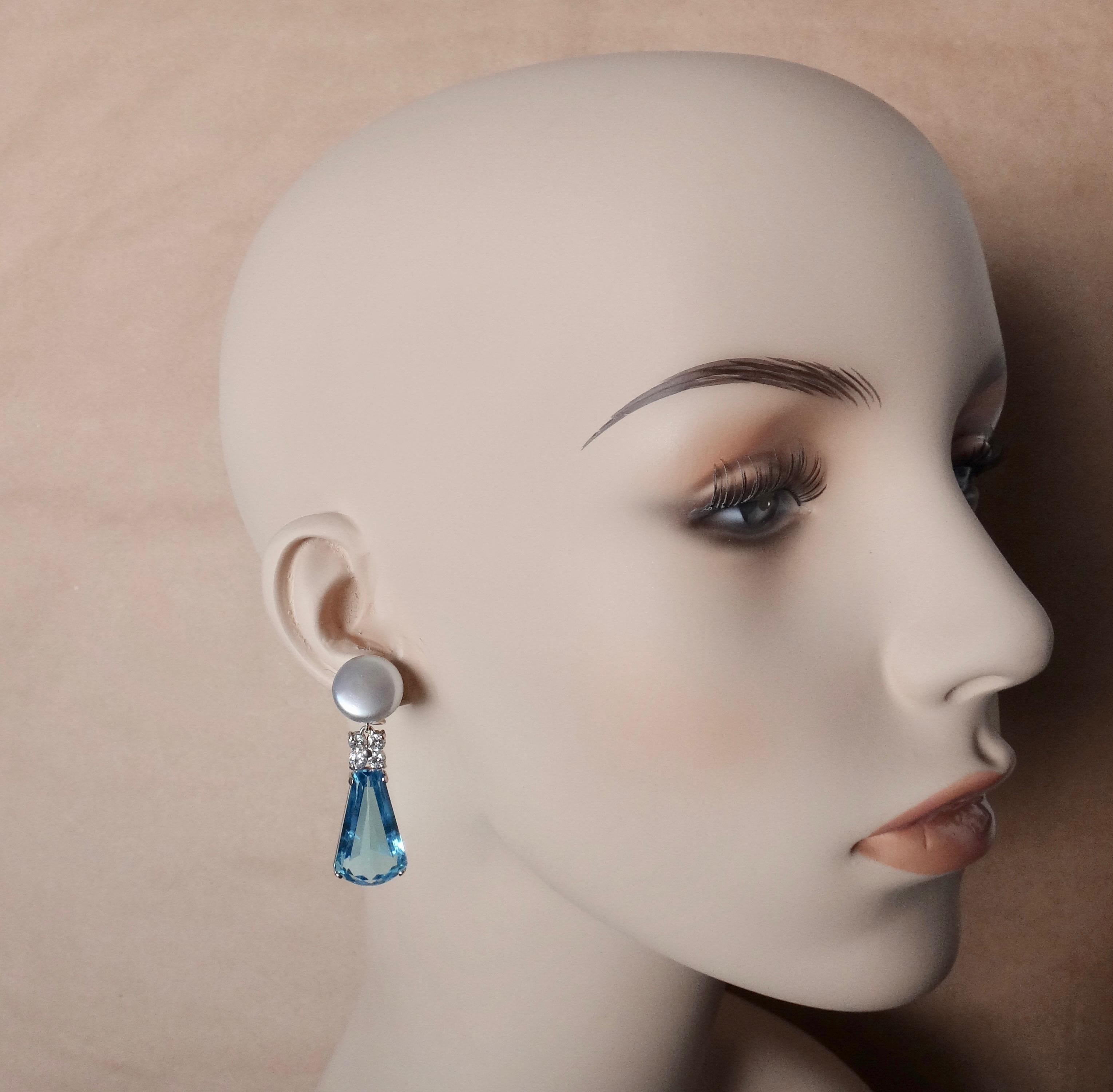 Swiss blue topaz in a whimsical keystone cut are featured in these elegant dangle earrings.  The gems are exceedingly well cut, polished and matched.  The blue topaz are complimented by white diamonds and a pair of 15mm gray toned button pearls of
