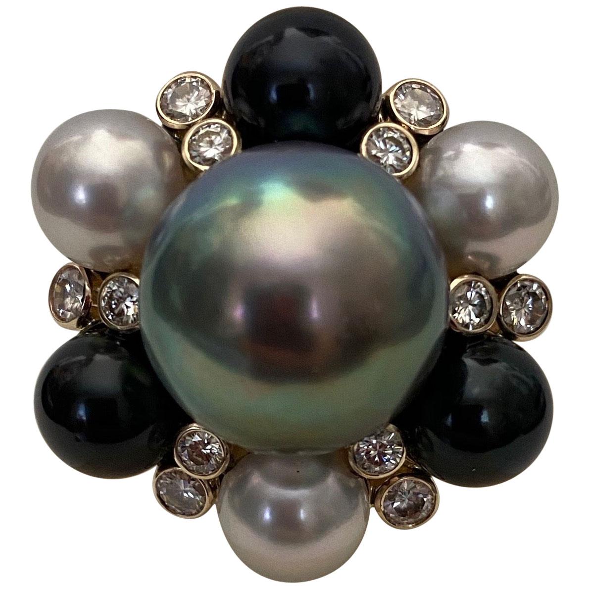 A 15mm dove gray Tahitian pearl is featured in this impressive cocktail ring.  The gem quality pearl has a  lustrous rainbow nacre reflecting blues, pinks and greens.  The pearl is surrounded by 3 black and 3 white Akoya pearls of gem quality.  The